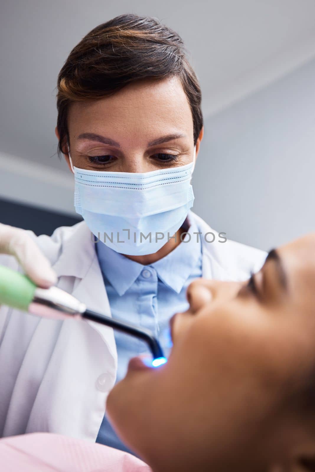 Finely skilled in the art of creating smiles. a dentist using a curing light on a patient during orthodontic treatment