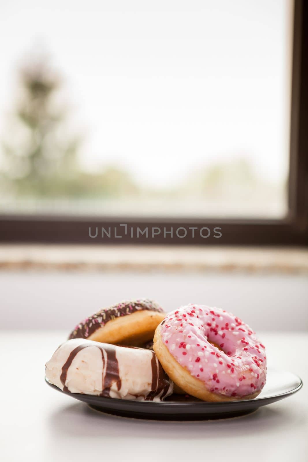 Plate with donuts next to window by DCStudio