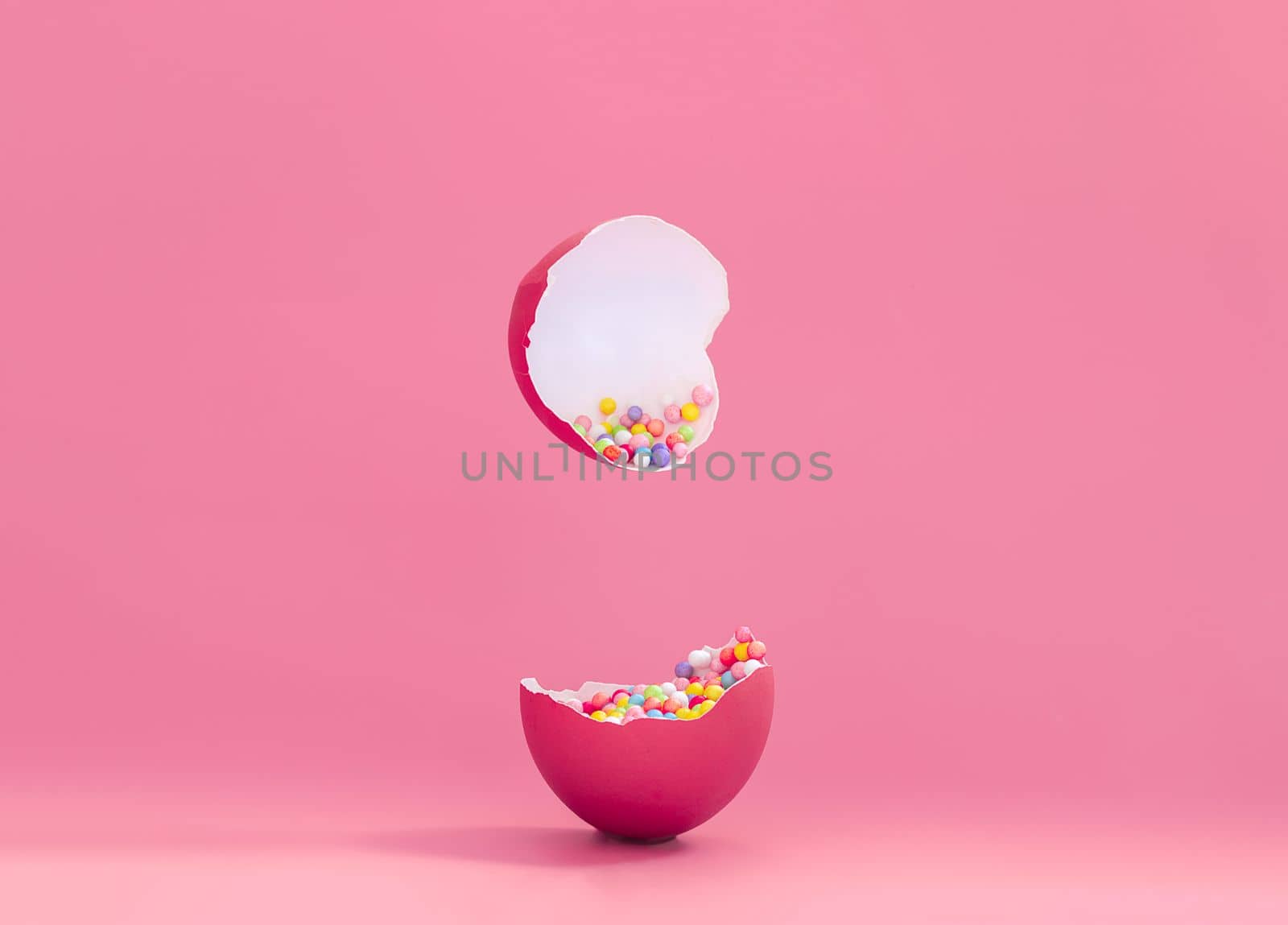 Broken decorative easter egg with colorful confetti. Minimal composition, painted egg magenta color on pastel pink background. Space for text. by Ri6ka