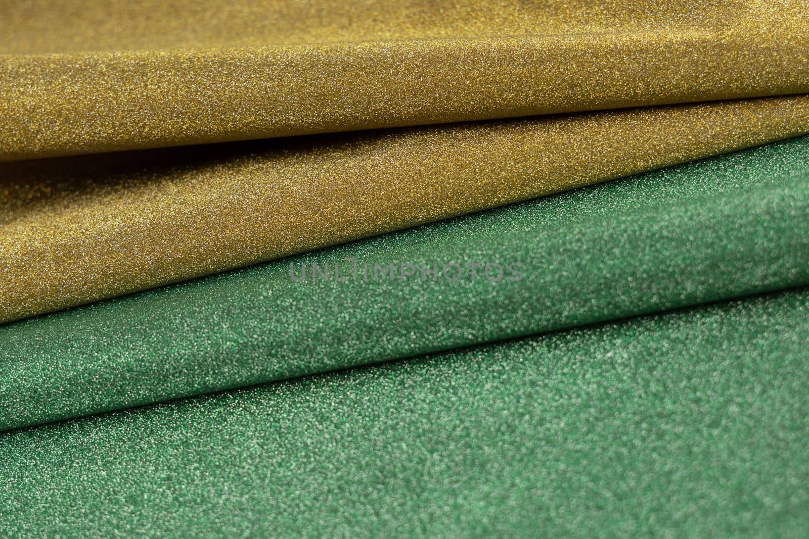 Golden and green wave shiny glitter paper texture. Shining luxurious fabric. Glimmering light green golden color, christmas background