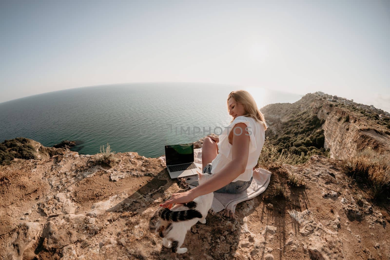 Woman sea laptop. Business woman petting cat and working on laptop by the sea. Close up on hands of pretty lady typing on computer outdoors summer day. Freelance, digital nomad and holidays concept. by panophotograph