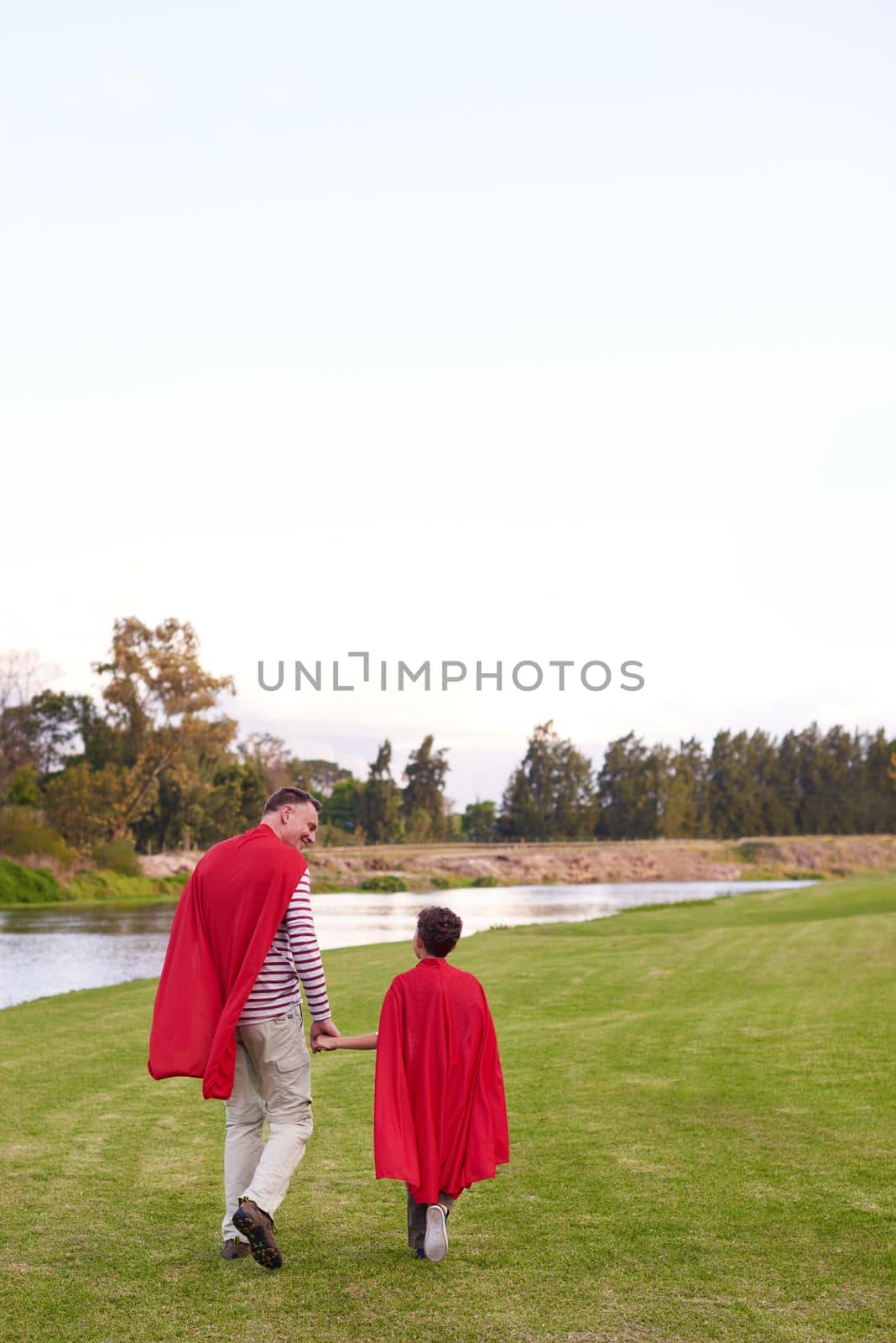 For them, being super is easy. a father and his young son pretending to be superheroes while playing outdoors