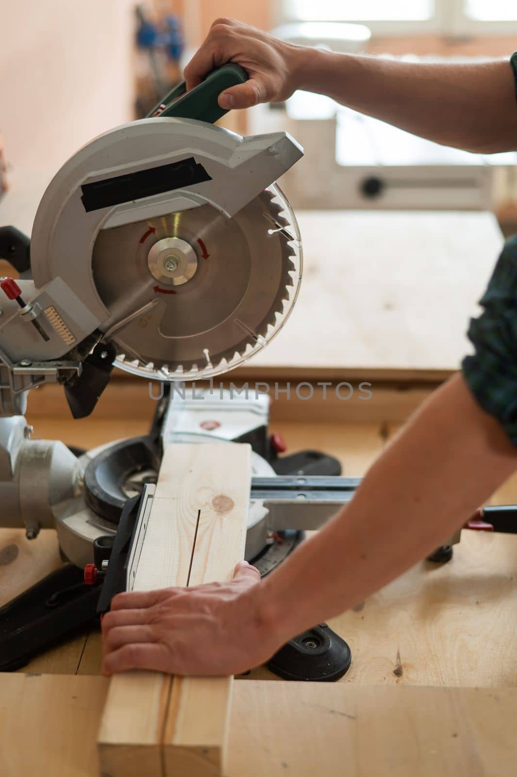 Master cuts the board with a circular saw in the workshop. by mrwed54