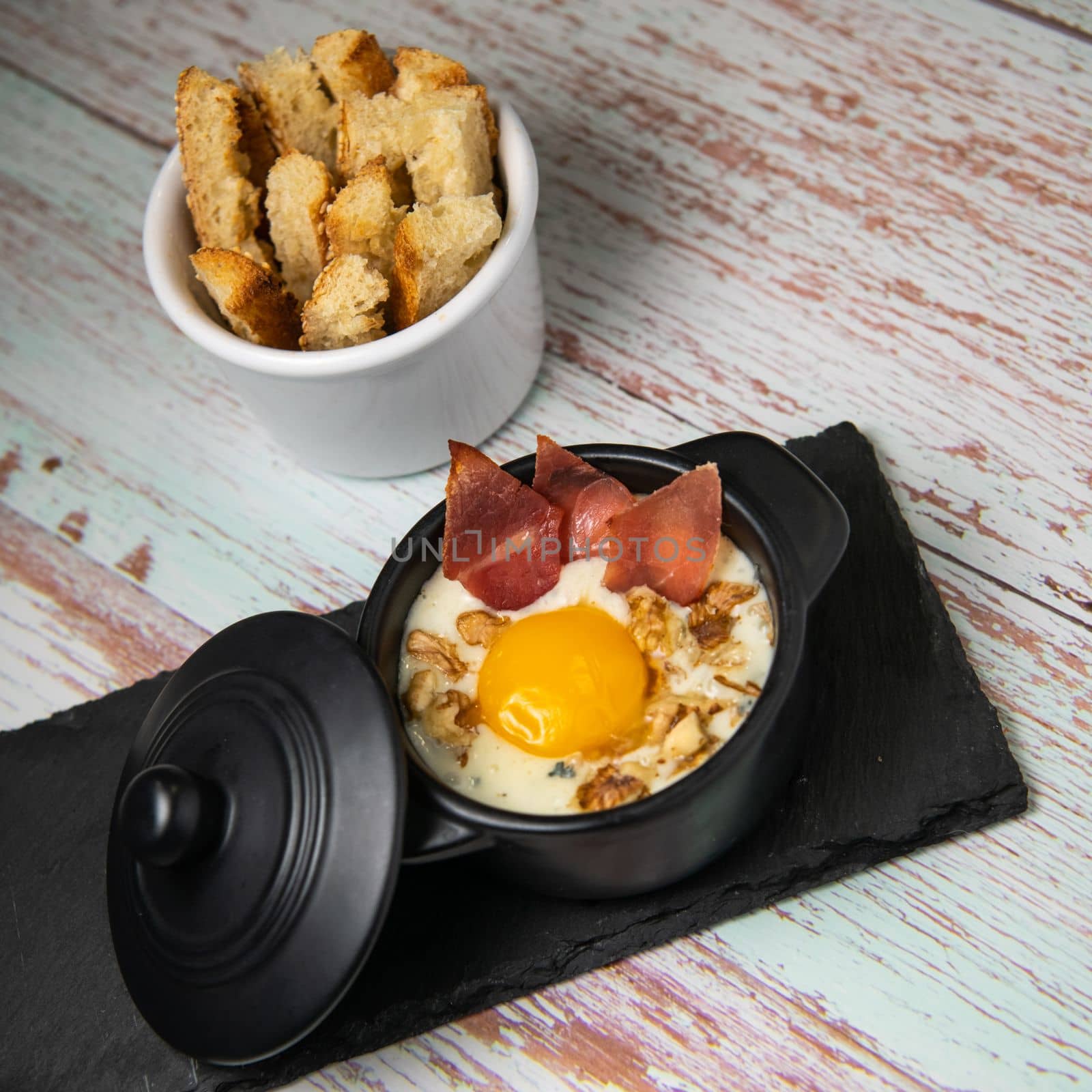 Recipe Oeuf cocotte with fresh cream sauce, Roquefort and walnuts, ham chips, toasted bread sticks. High quality photo