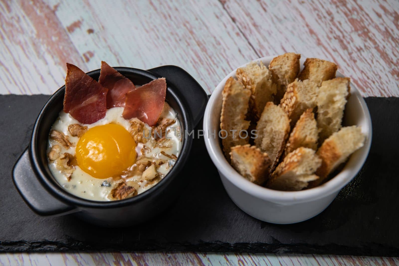 Recipe Oeuf cocotte with fresh cream sauce, Roquefort and walnuts, ham chips, toasted bread sticks. High quality photo