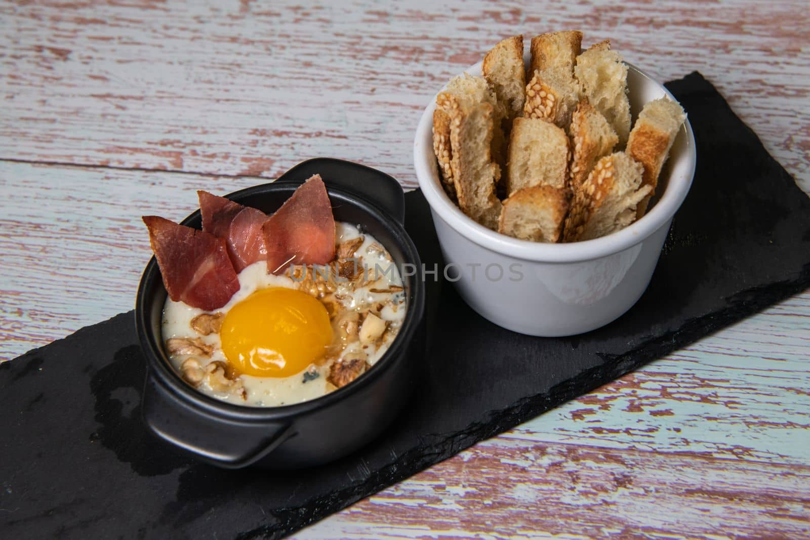 Recipe Oeuf cocotte with fresh cream sauce, Roquefort and walnuts, ham chips, toasted bread sticks. High quality photo