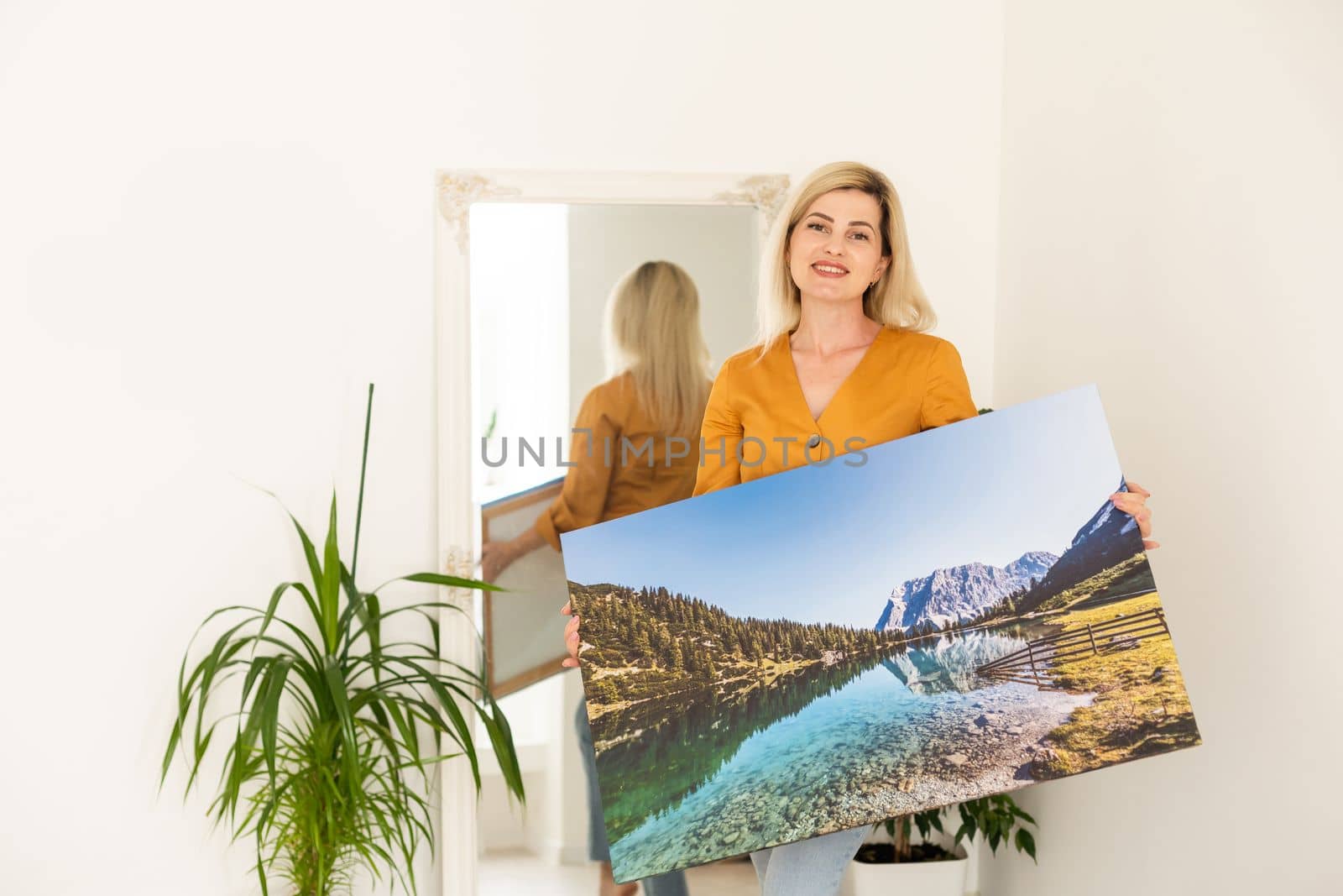Woman hanging a photo canvas on a wall. by Andelov13