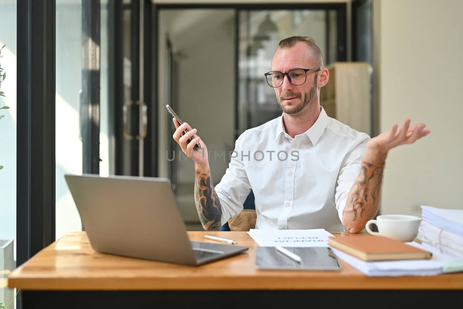 Upset male office worker staring at laptop screen, feeling irritated with the internet connection speed by prathanchorruangsak