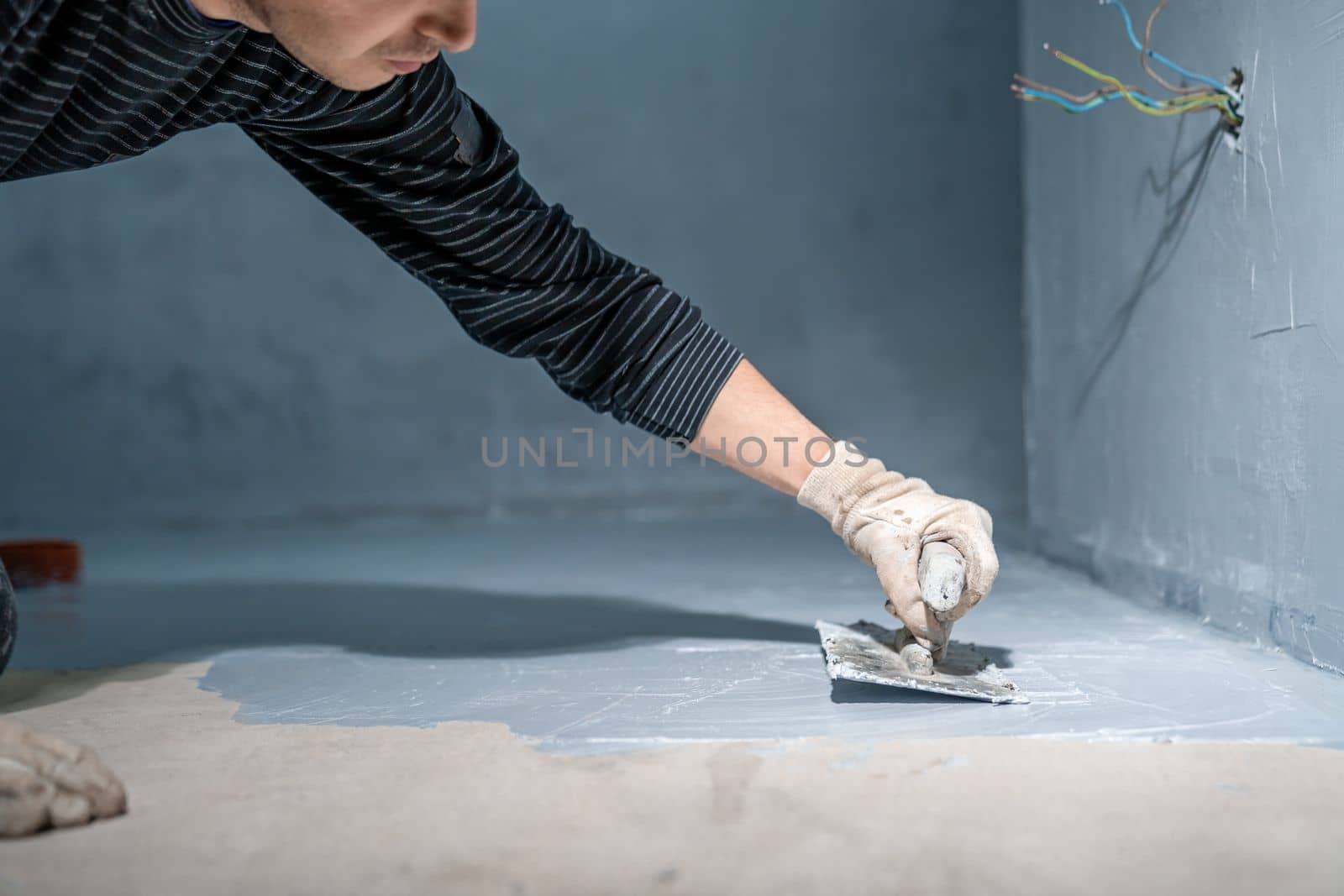 bricklayer works with trowel in room. High quality photo