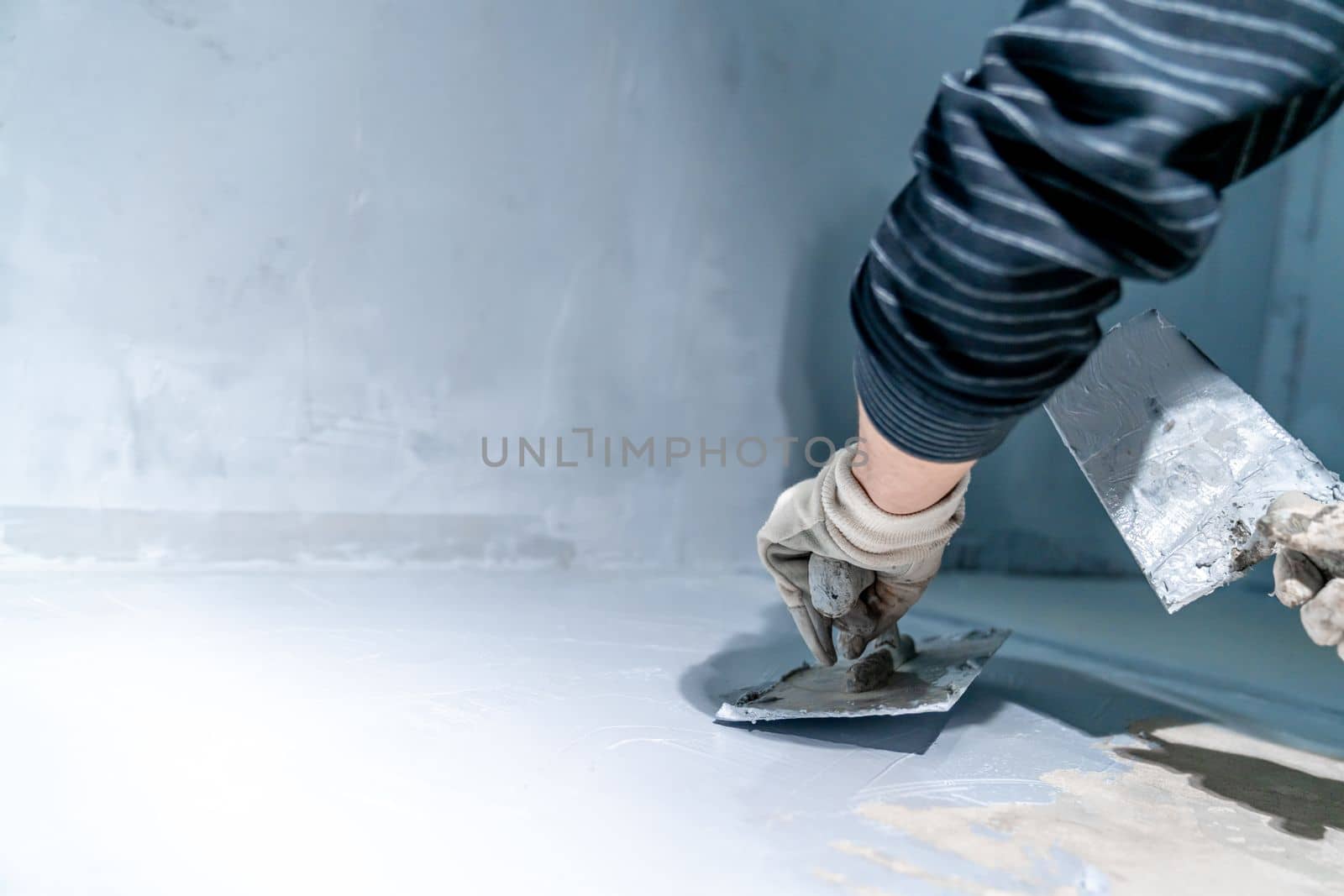 work with trowel on floor and wall in new room in building. High quality photo