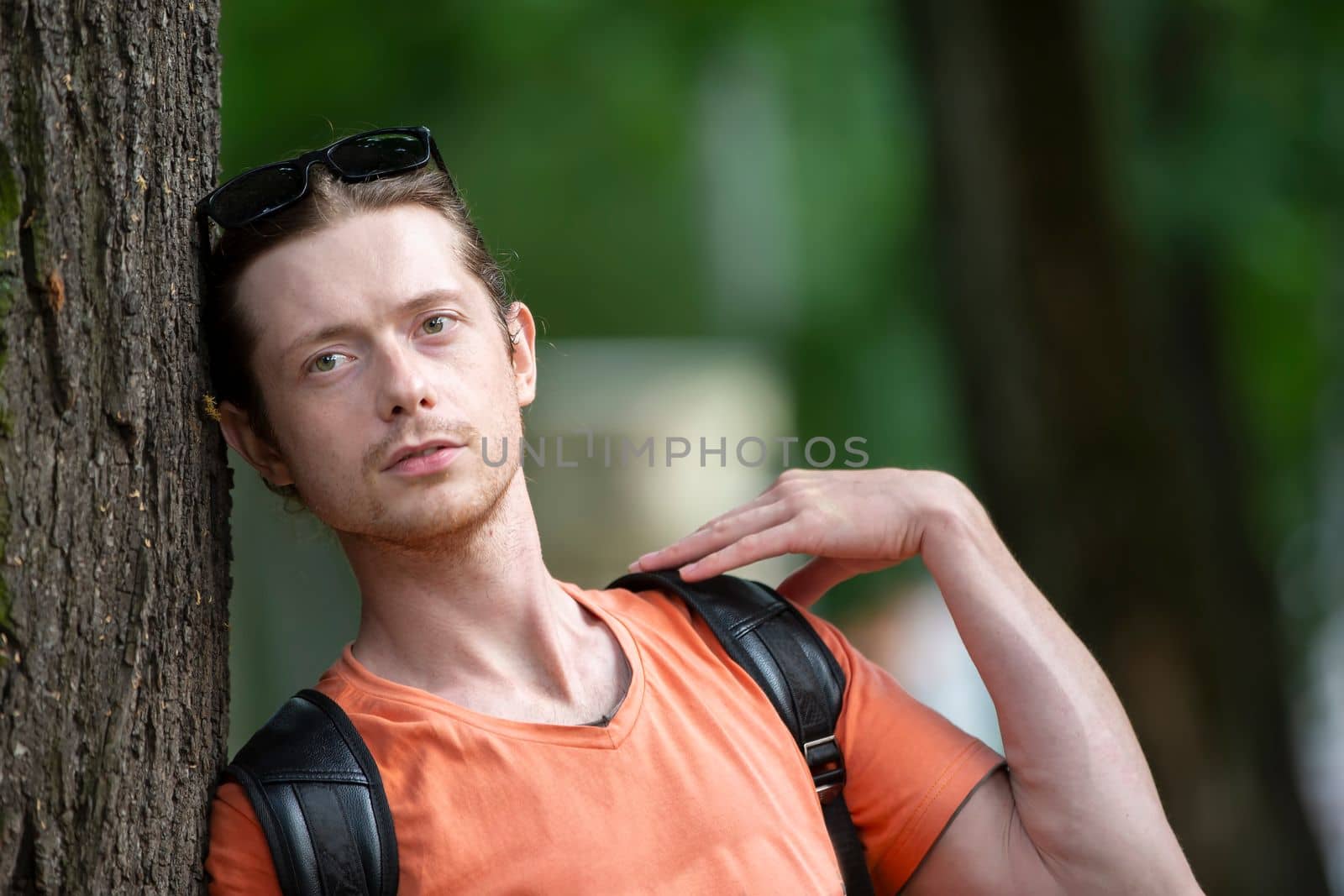 June 23, 2019 Belarus. Gomil city. City street. A man in casual clothes leaned against a tree. by Sviatlana