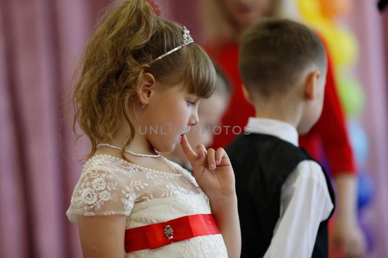 Belarus, Gomil city, May 16, 2019 Matinee in kindergarten.Little girl pensive on the background of a blurred figure of a little boy. Psychology of children's relations.