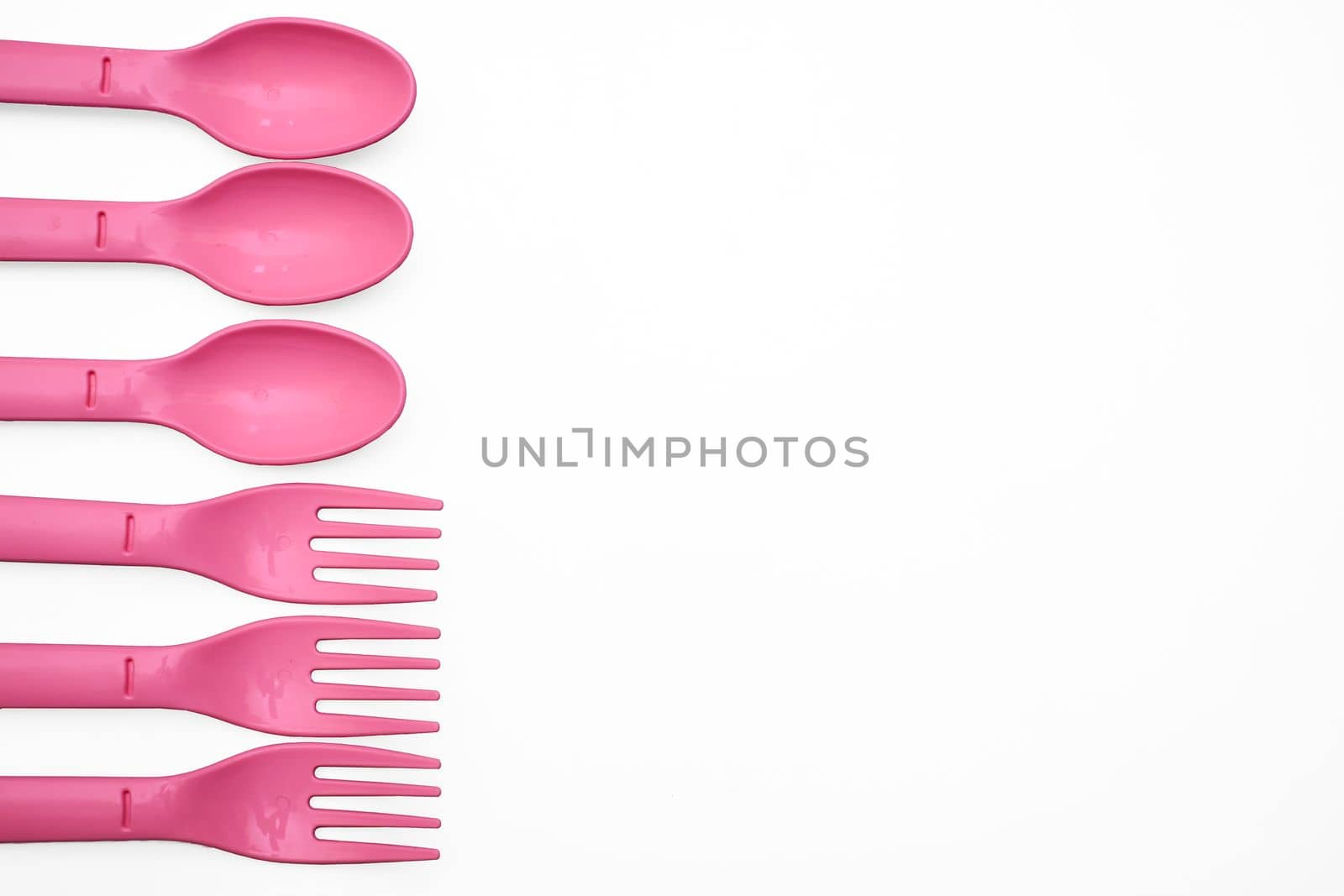 put, lay, or stand something in a specified place or position. Pink plastic camping spoons and forks isolated on white.