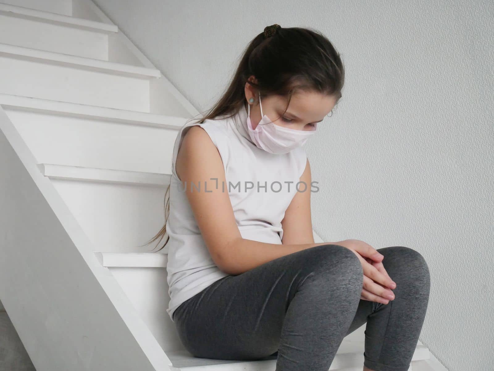 Student girl wearing a mask seating on stairs after COVID-19 quarantine and lockdown, sad and tired of not going to school with her friends. by Jyliana