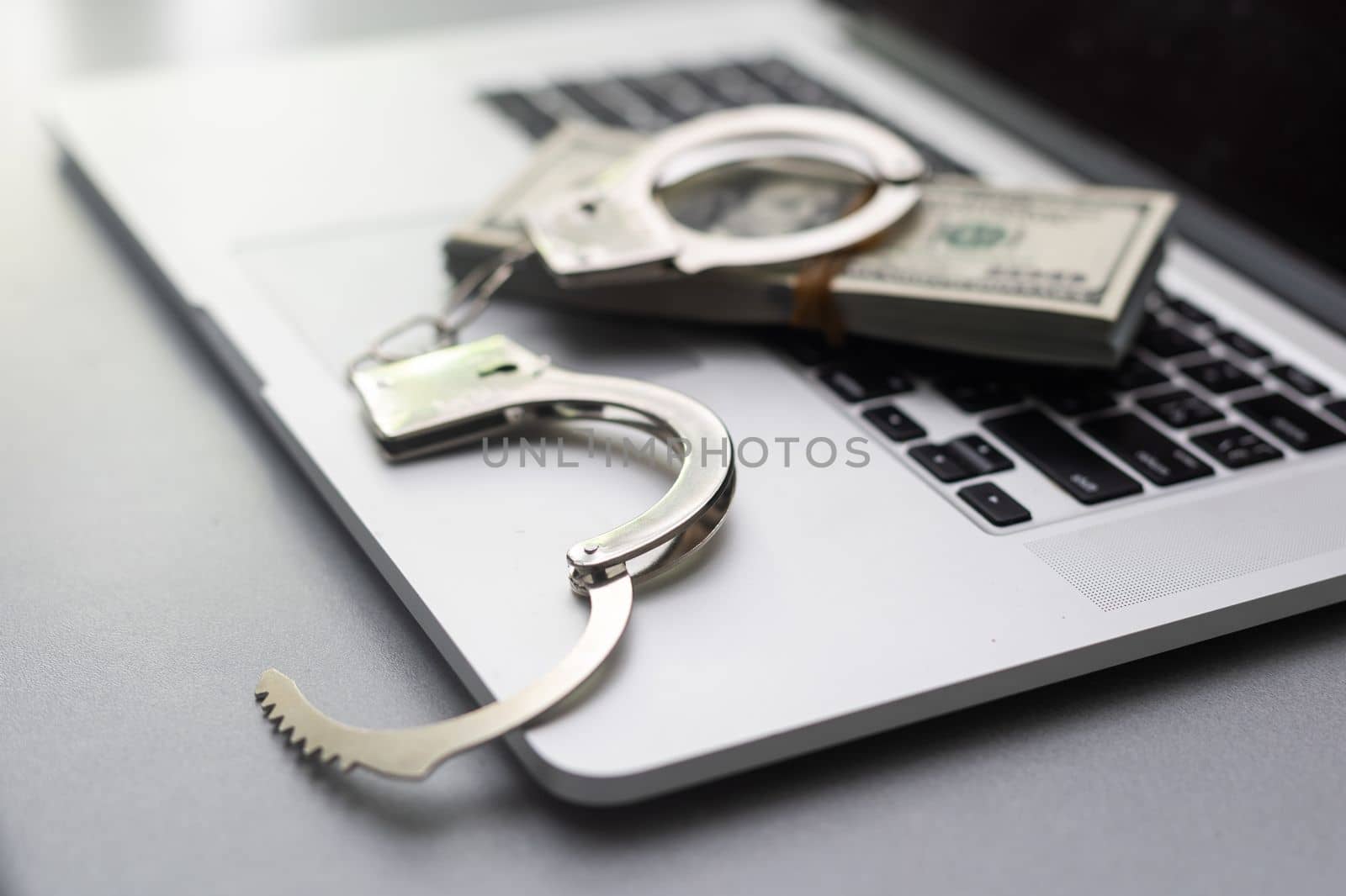 Cyber crime legal law police handcuffs on a hundred dollar bills with computer keyboard technology of criminal taking fingerprint on paper by Andelov13