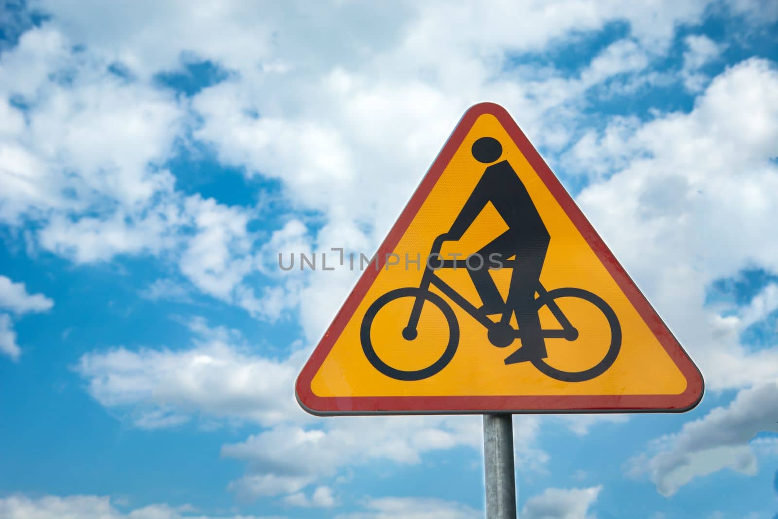 Yellow-red road sign cyclists against the blue sky