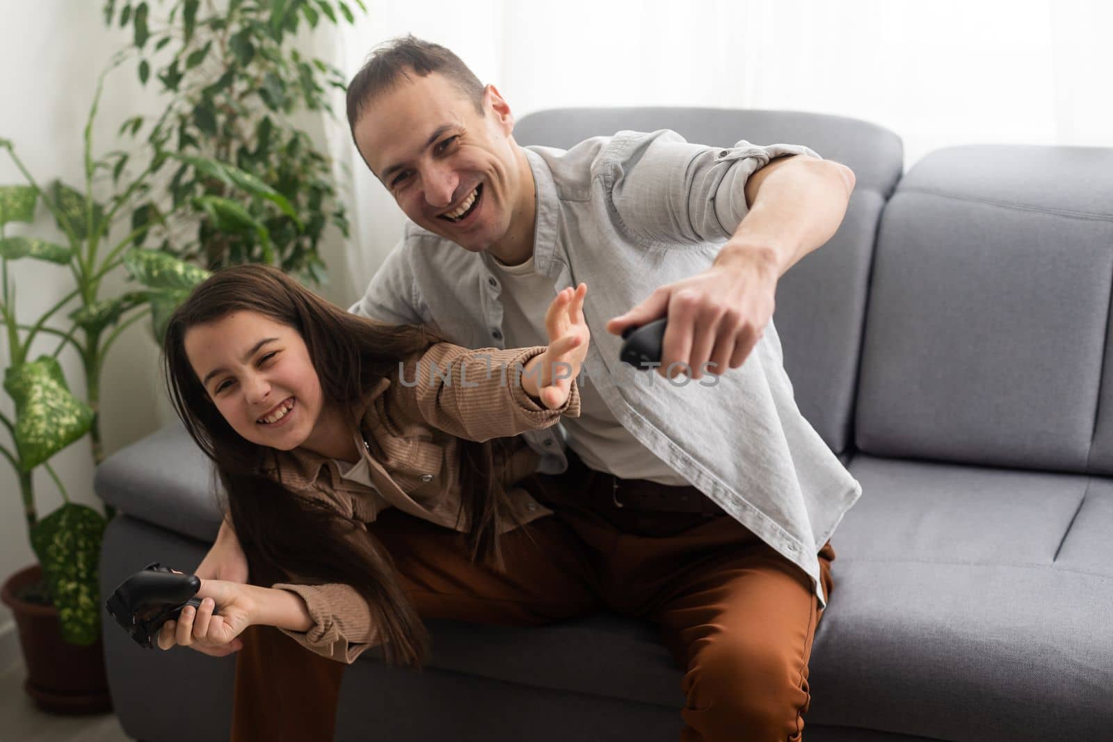 excited father and daughter playing video game at home. by Andelov13