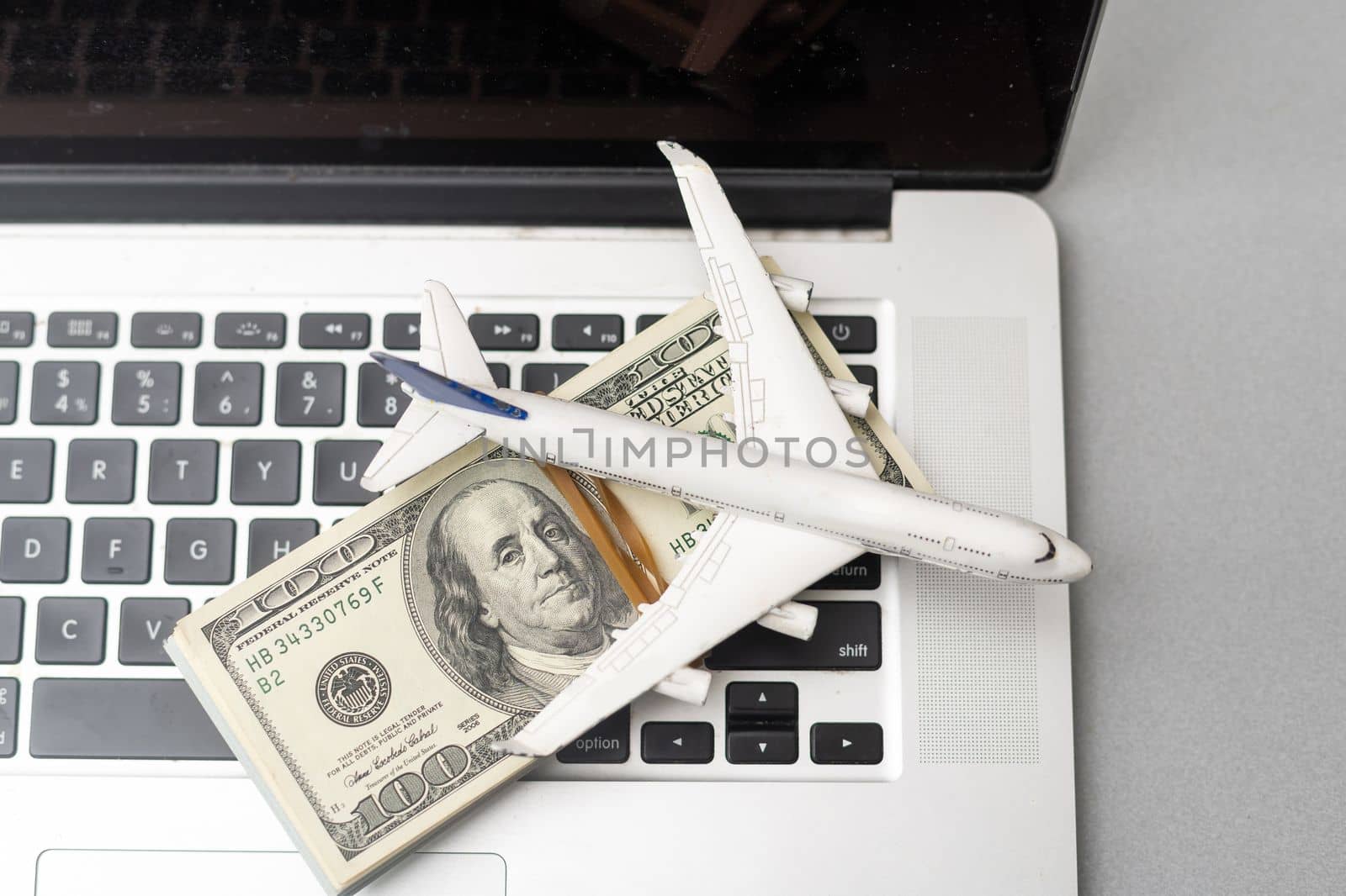 plane, money and keyboard. online purchase of airline tickets on a gray wooden table.
