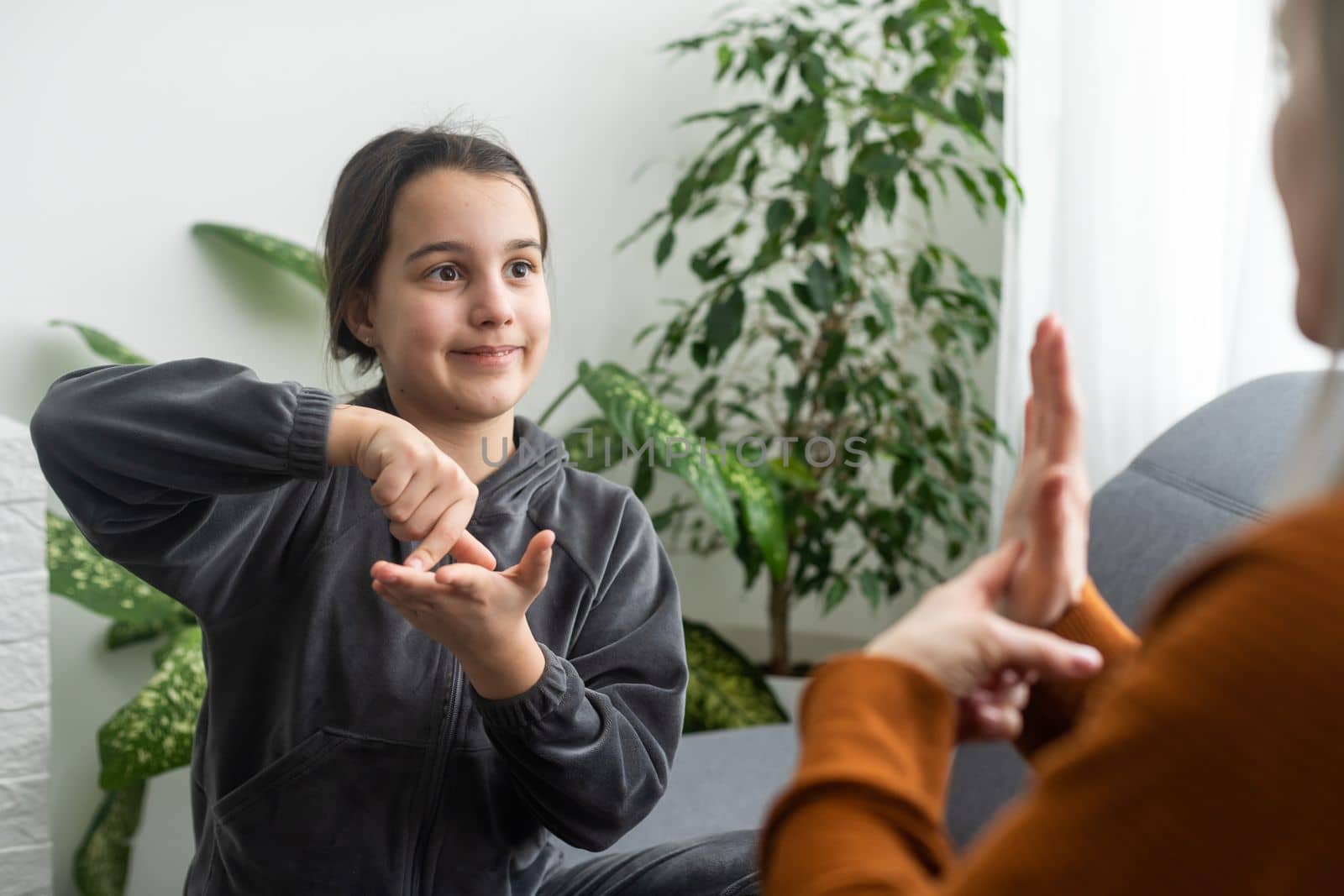 daughter talk with middle aged mother people using sign language, family sitting on armchair side view, teacher teach teenager deaf-mute girl to visual-manual gestures symbols concept image by Andelov13