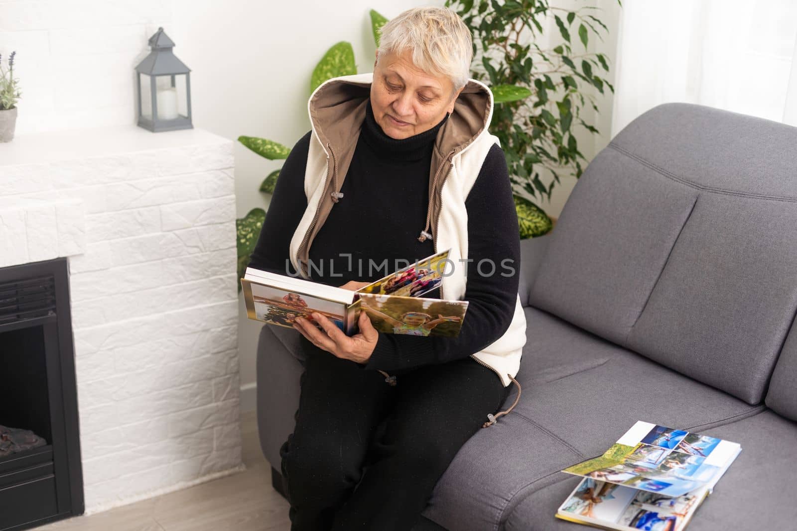 Senior lady looking at old photographs in an album, remembering her past