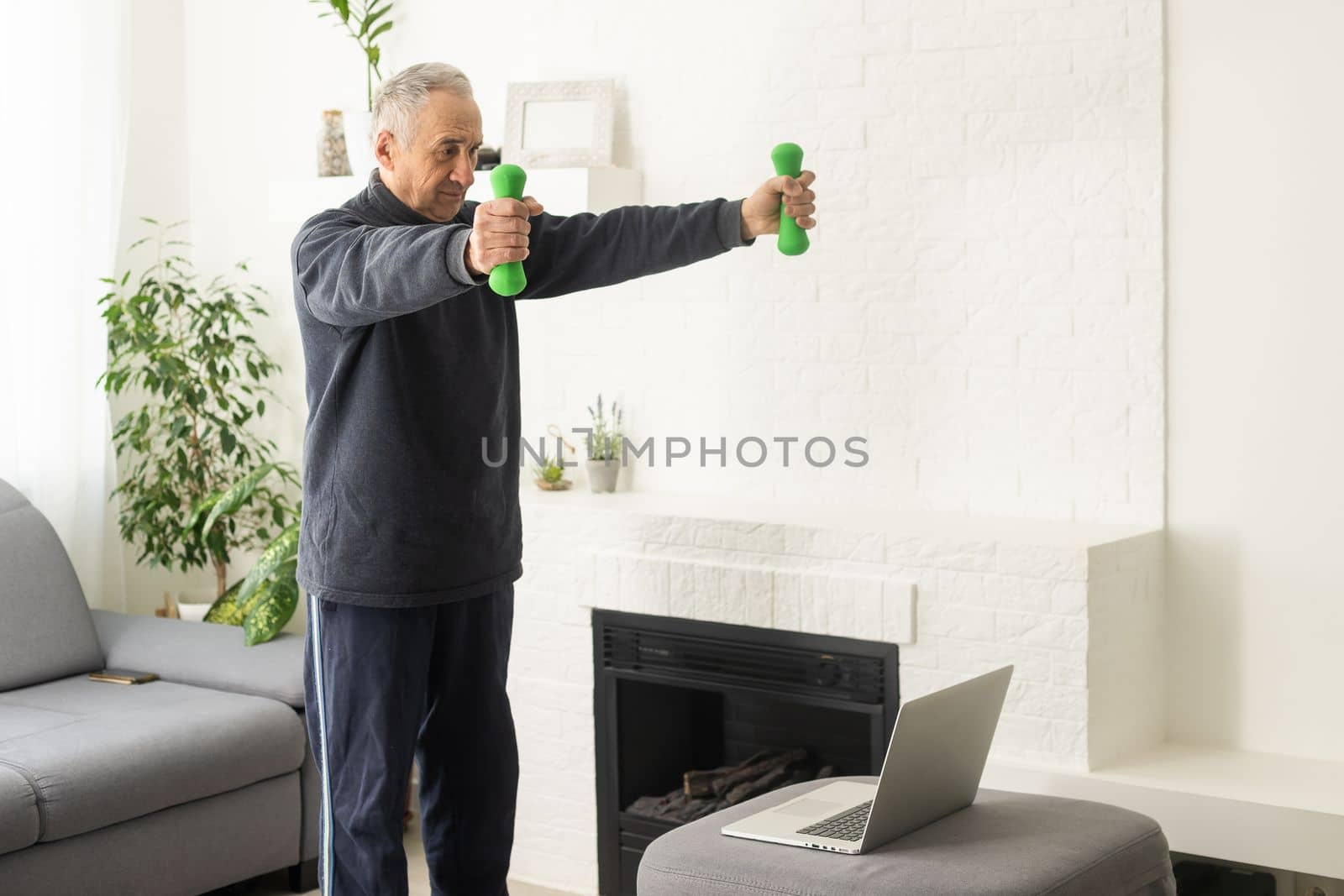 Online workout. elderly man doing exercise with online tutorial at home, panorama, free space by Andelov13