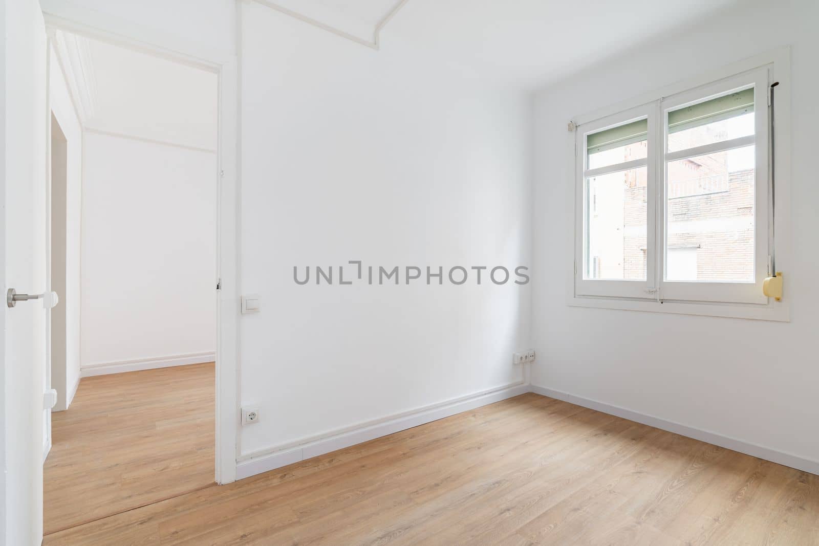 Bright white spacious unfurnished apartment with an window and wooden textured laminate. Concept of modern building or moving to new apartment. Interior design renovation.
