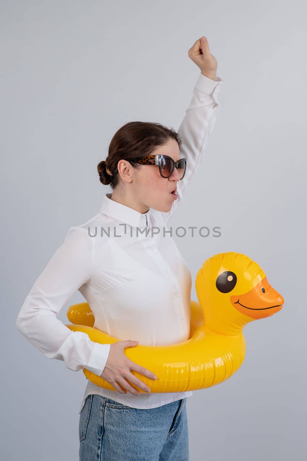 Excited woman in white shirt dreaming about vacation, wearing sunglasses and inflatable duck