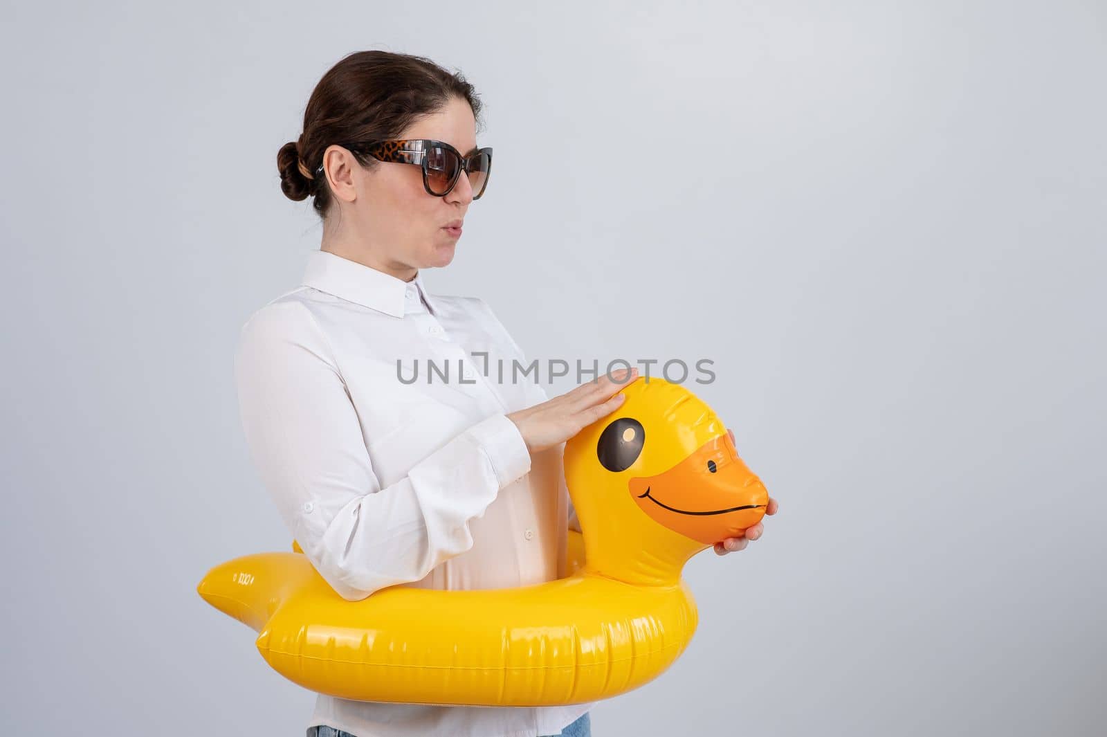 Caucasian woman in a white shirt dreaming of a vacation and wearing sunglasses and an inflatable duck