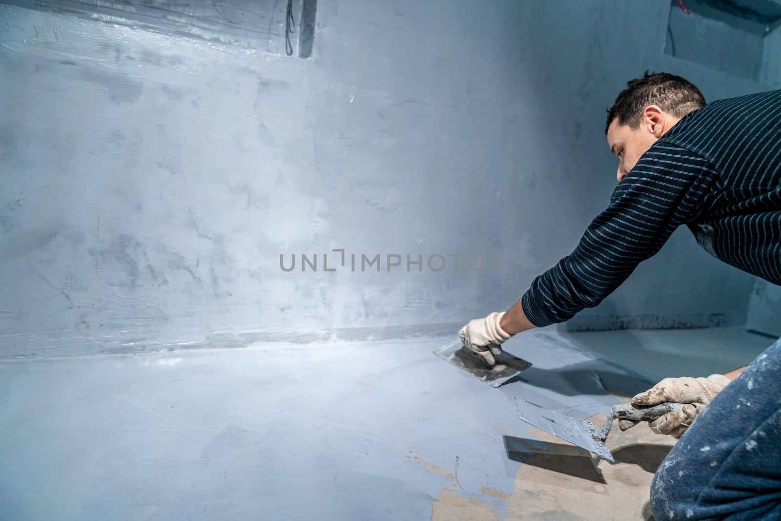 spreading the insulation on the concrete with a trowel.