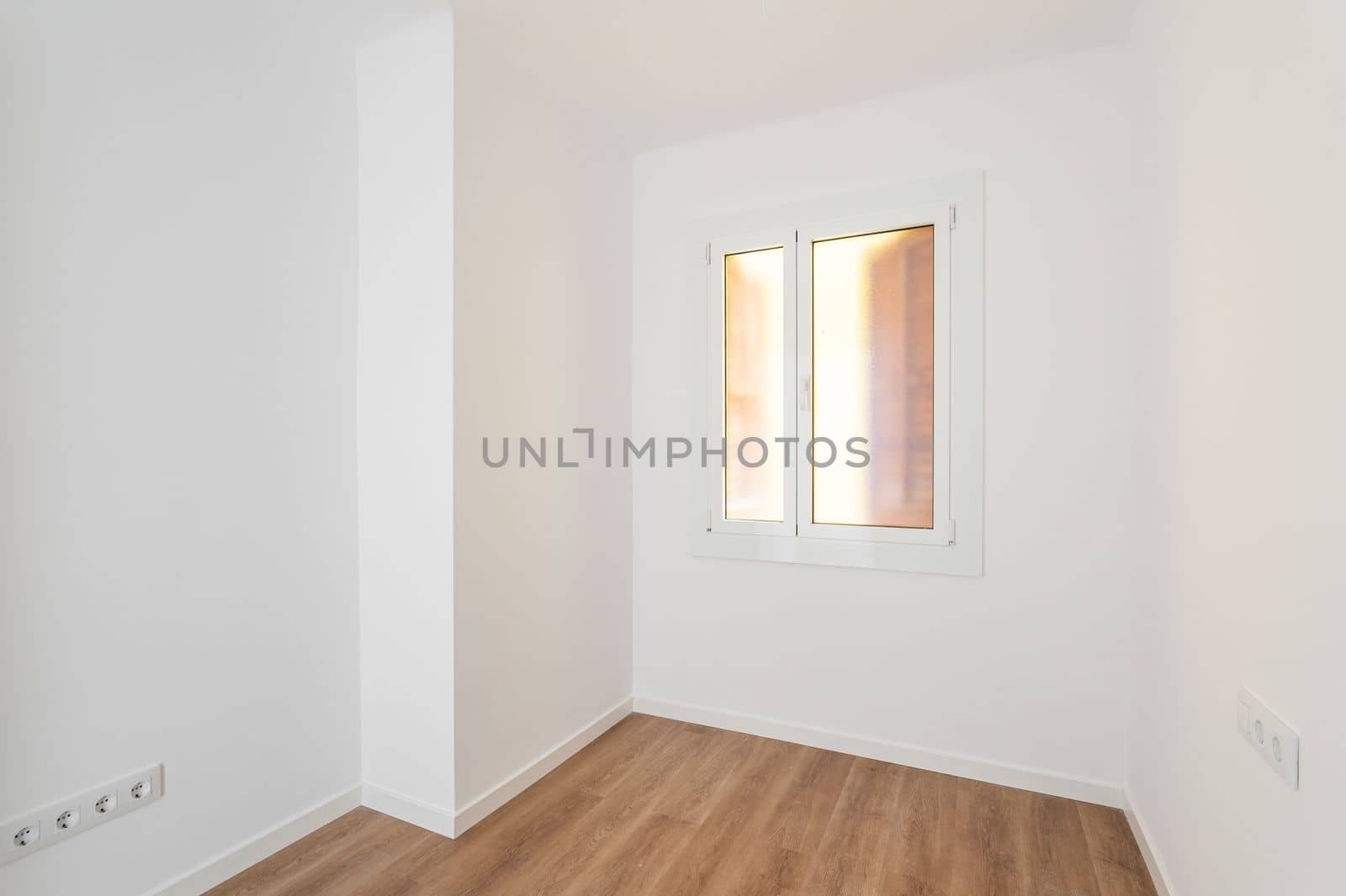 Part of an empty room with white walls, brown parquet. Plastic window in wall with frosted translucent glass. Socket is built into wall for simultaneous connection of several electrical appliances. by apavlin