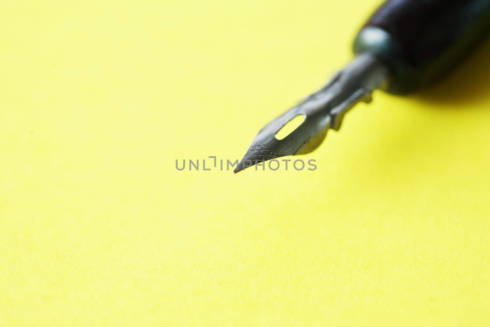 Closeup of nice vintage ink pen on empty yellow paper