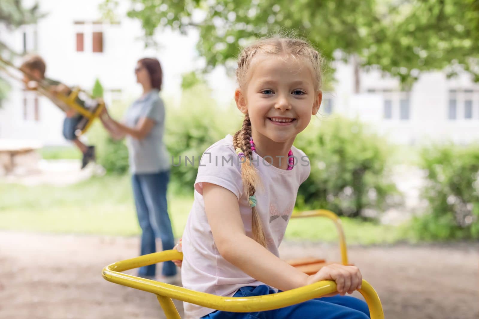 Portrait of a beautiful girl on the playground on a swing by Godi