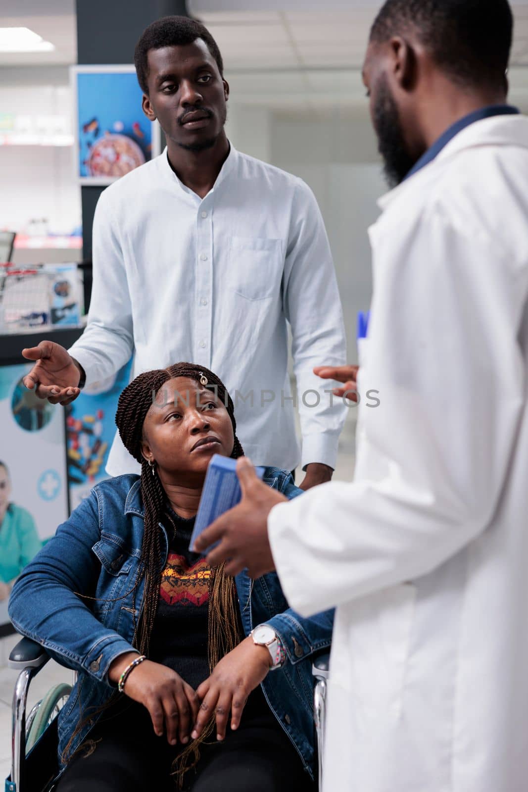 African american woman in wheelchair talking with pharmacist in drugstore, buying prescription treatment, chemist recommending medicaments. Client and pharmacy store consultant, all black team