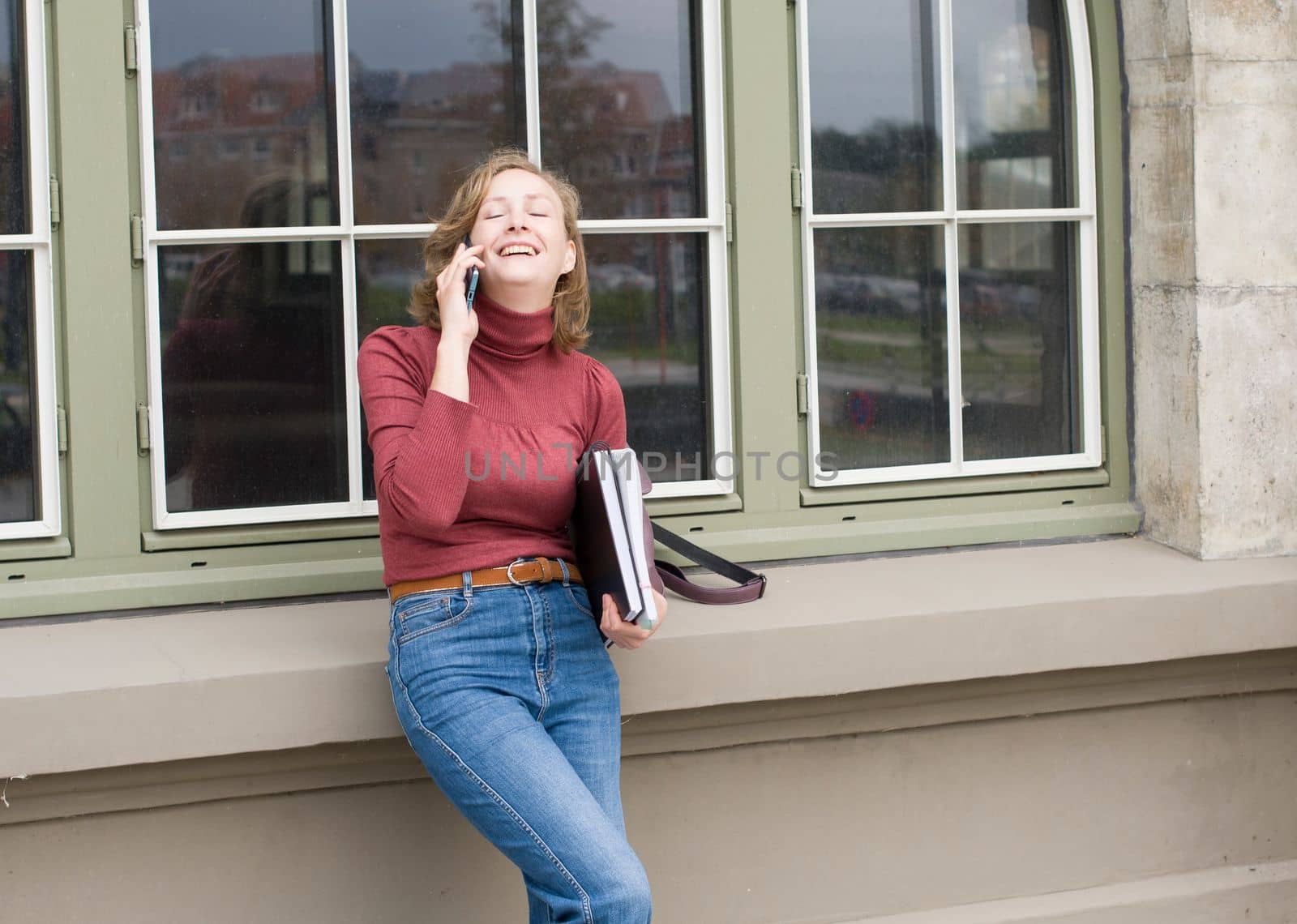 a young caucasian girl returns to college, stands with a backpack and notebooks and talks on the phone in a laugh, back to school, High quality photo