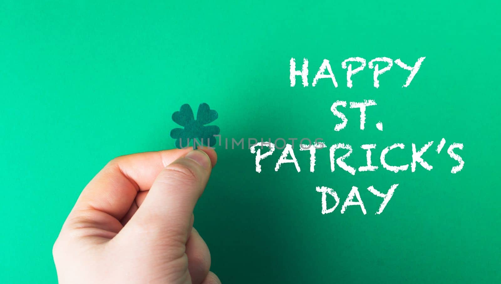 man's hand holding a four leaf clover. Green Happy Saint Patrick's Day Flat LayHigh quality photo