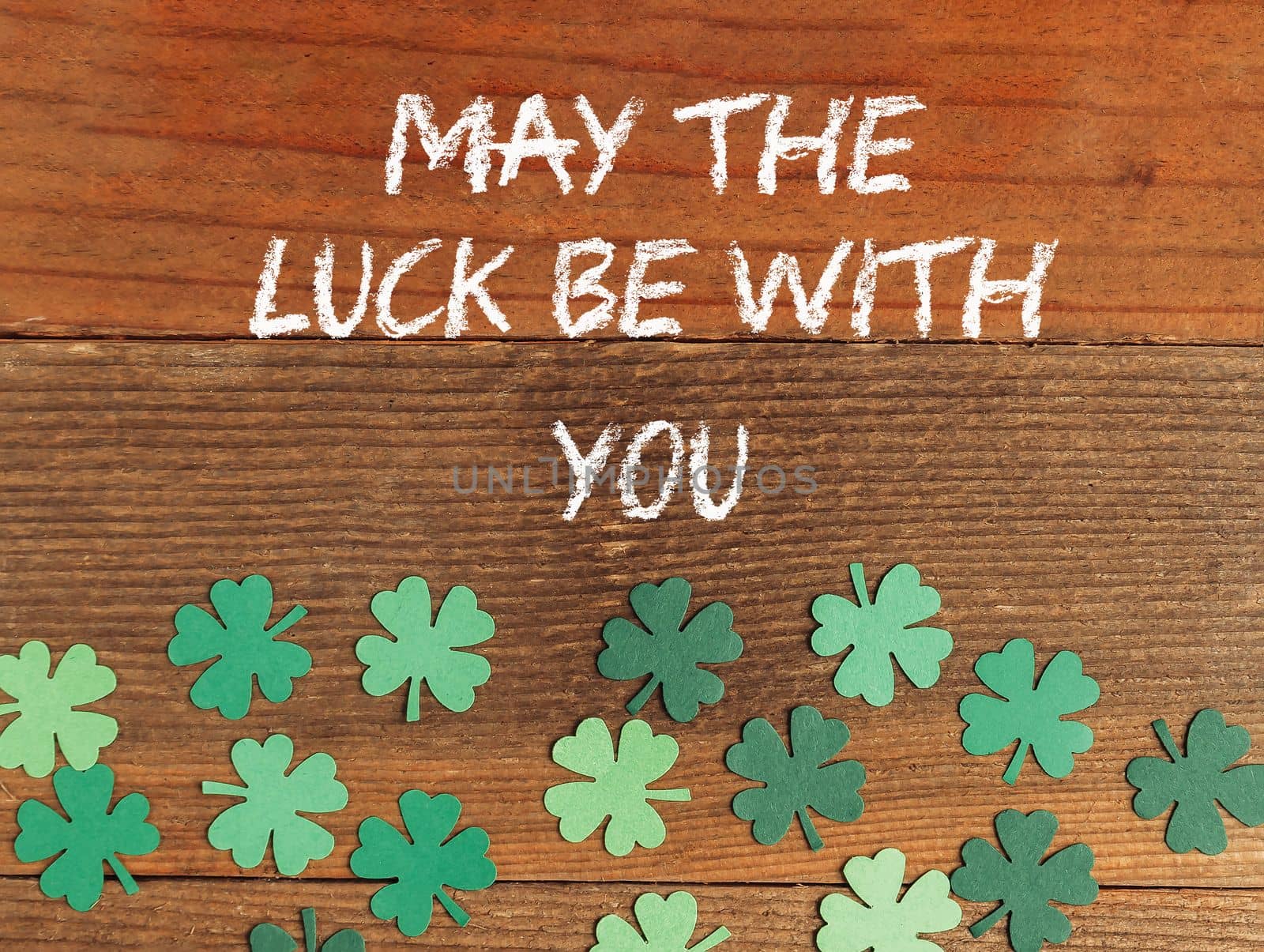 May The Luck Be With You retro St Patrick's Day on a wooden background lies a leprechaun hat with clover leaves. High quality photo