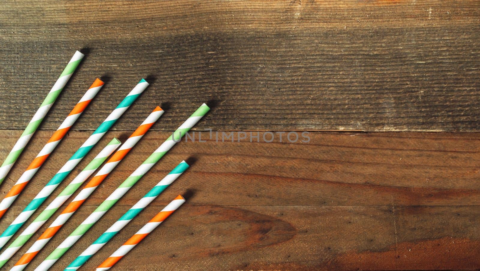 Multicolored straws for St. Patrick's Day for cocktails on a rustic wooden background with copy space