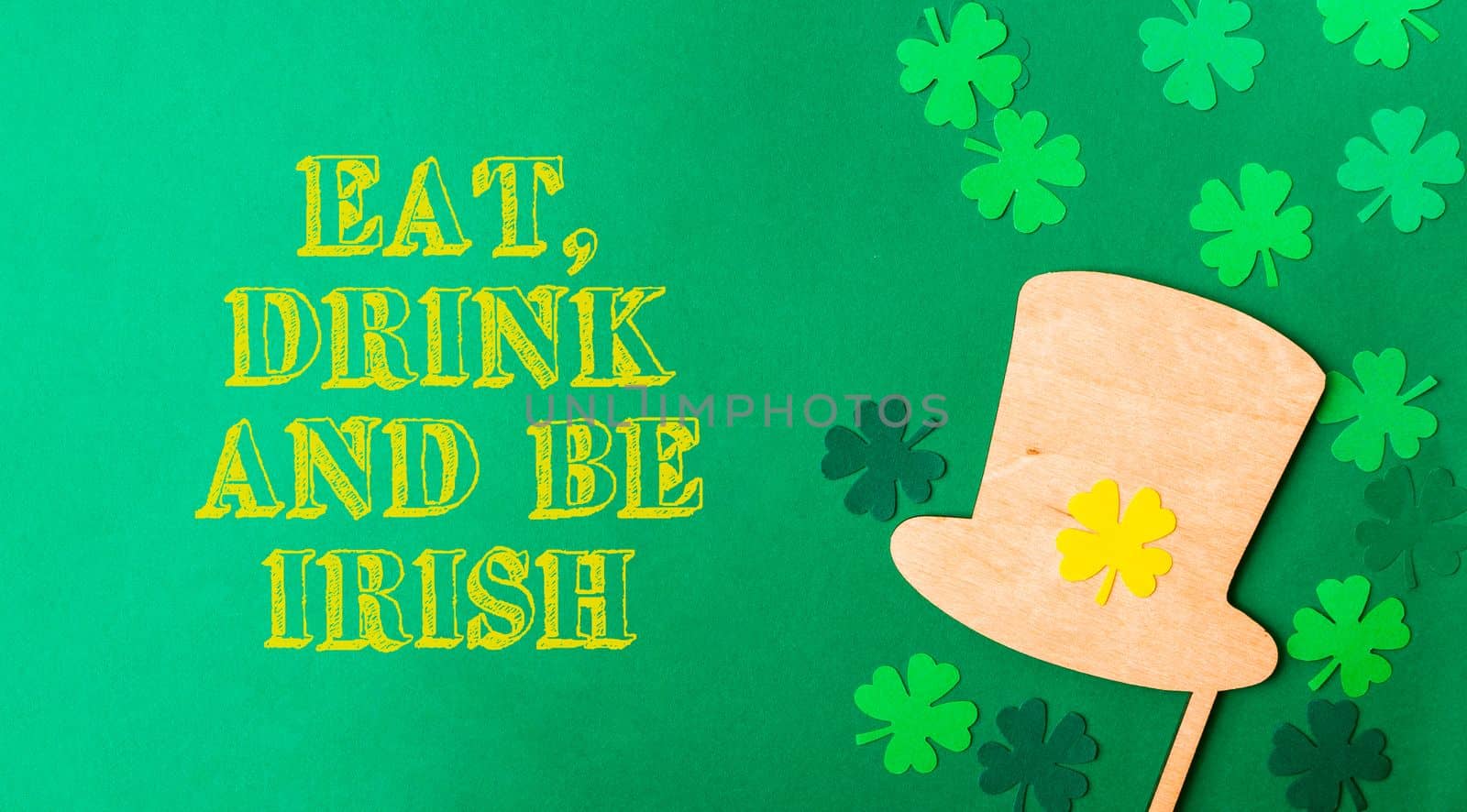 lettering eat, drink and be Irish on green background with clover and leprechaun hat. High quality photo