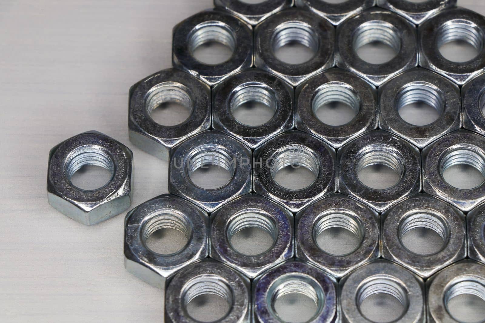 Threaded metal hex nuts neatly sorted on white surface