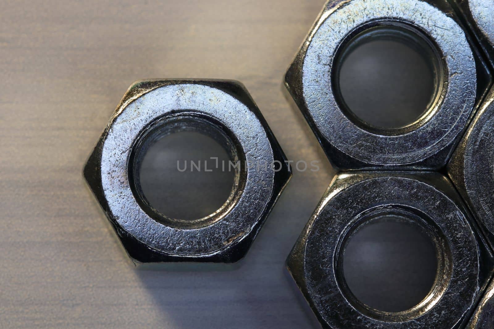 Threaded metal hex nuts close-up on textured surface