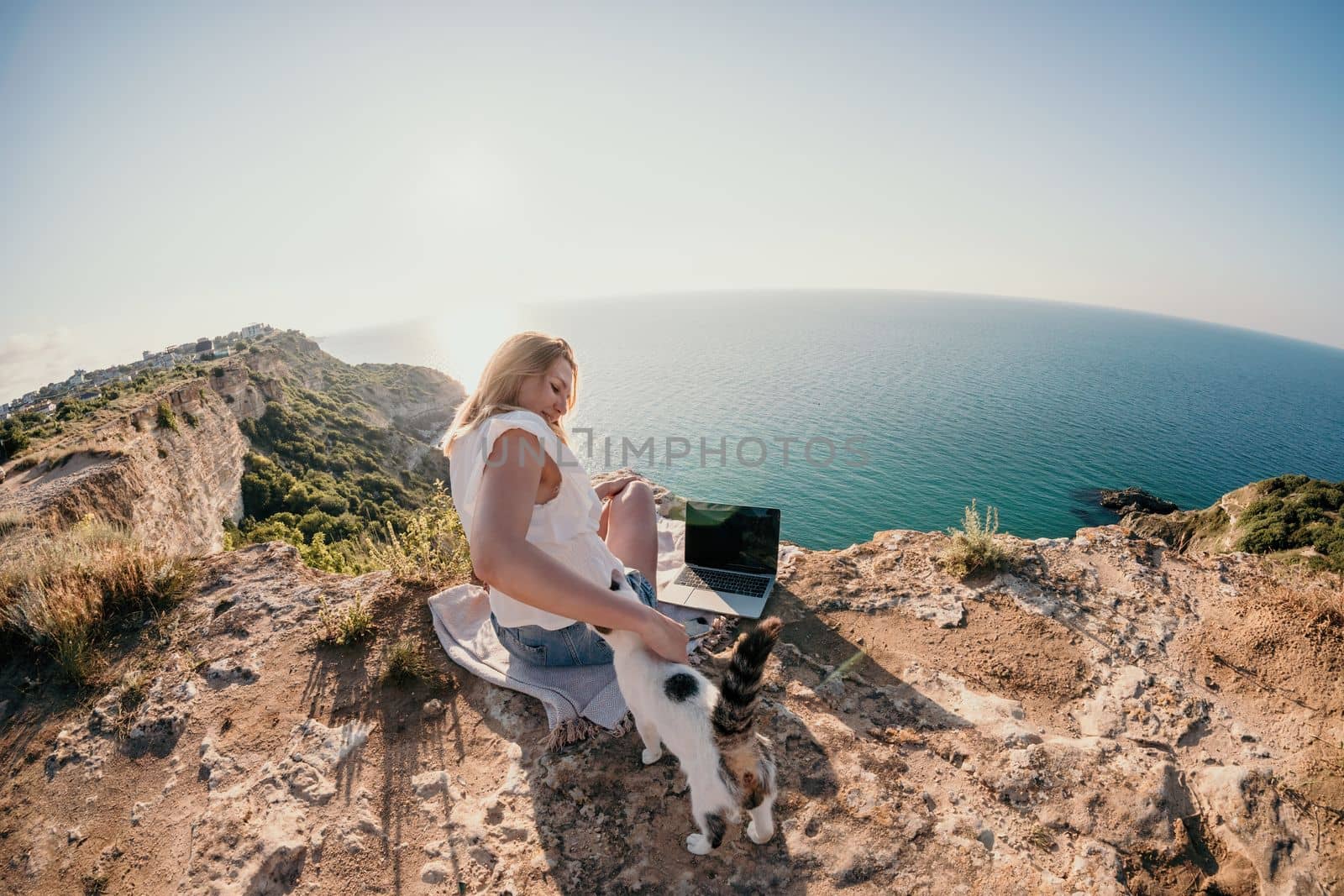 Woman sea laptop. Business woman in yellow hat working on laptop by sea. Close up on hands of pretty lady typing on computer outdoors summer day. Freelance, digital nomad, travel and holidays concept.