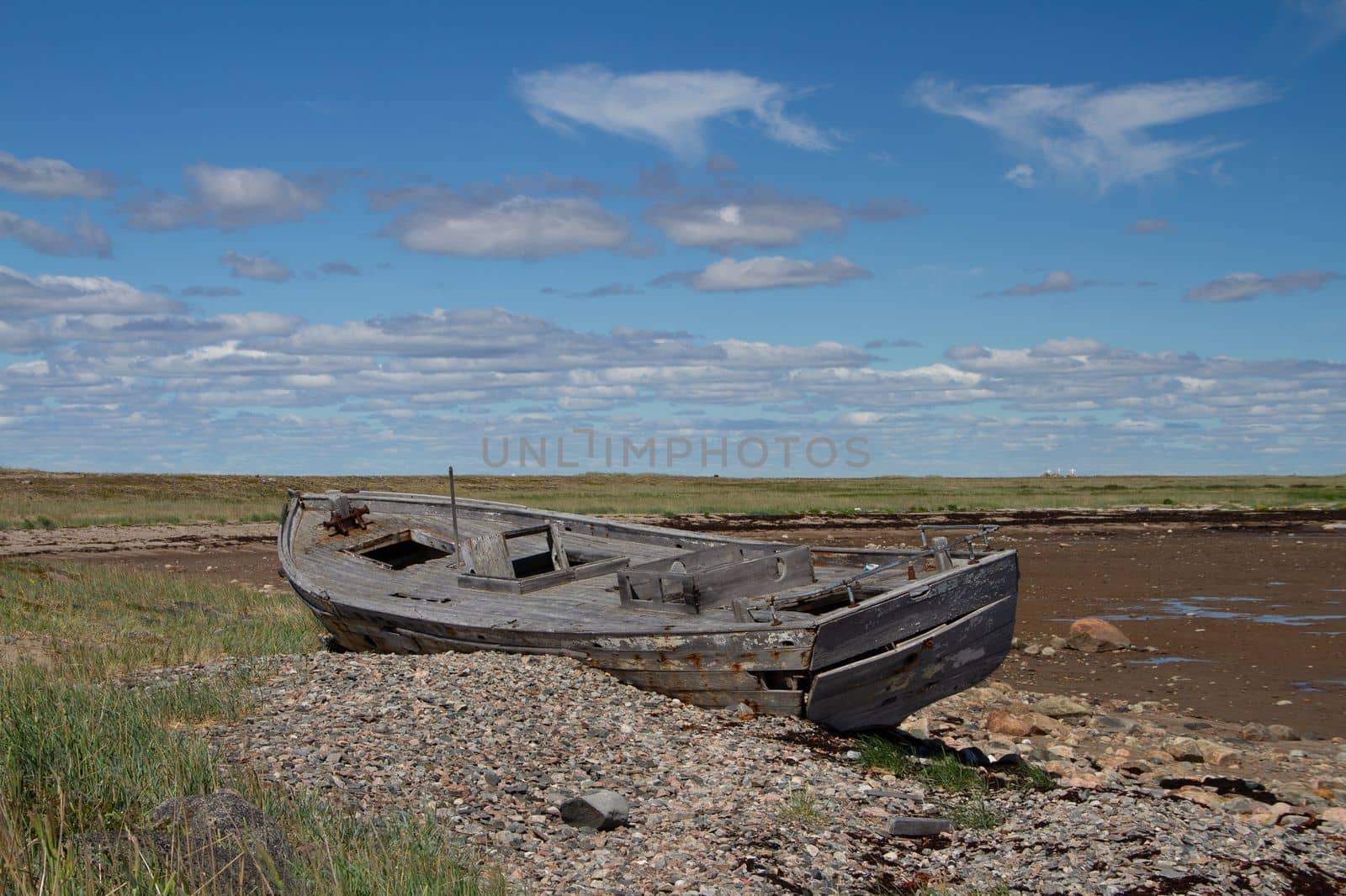 Side view of old wooden boat wrecked and stranded on a rocky shoreline, north of Arviat, Nunavut, Canada