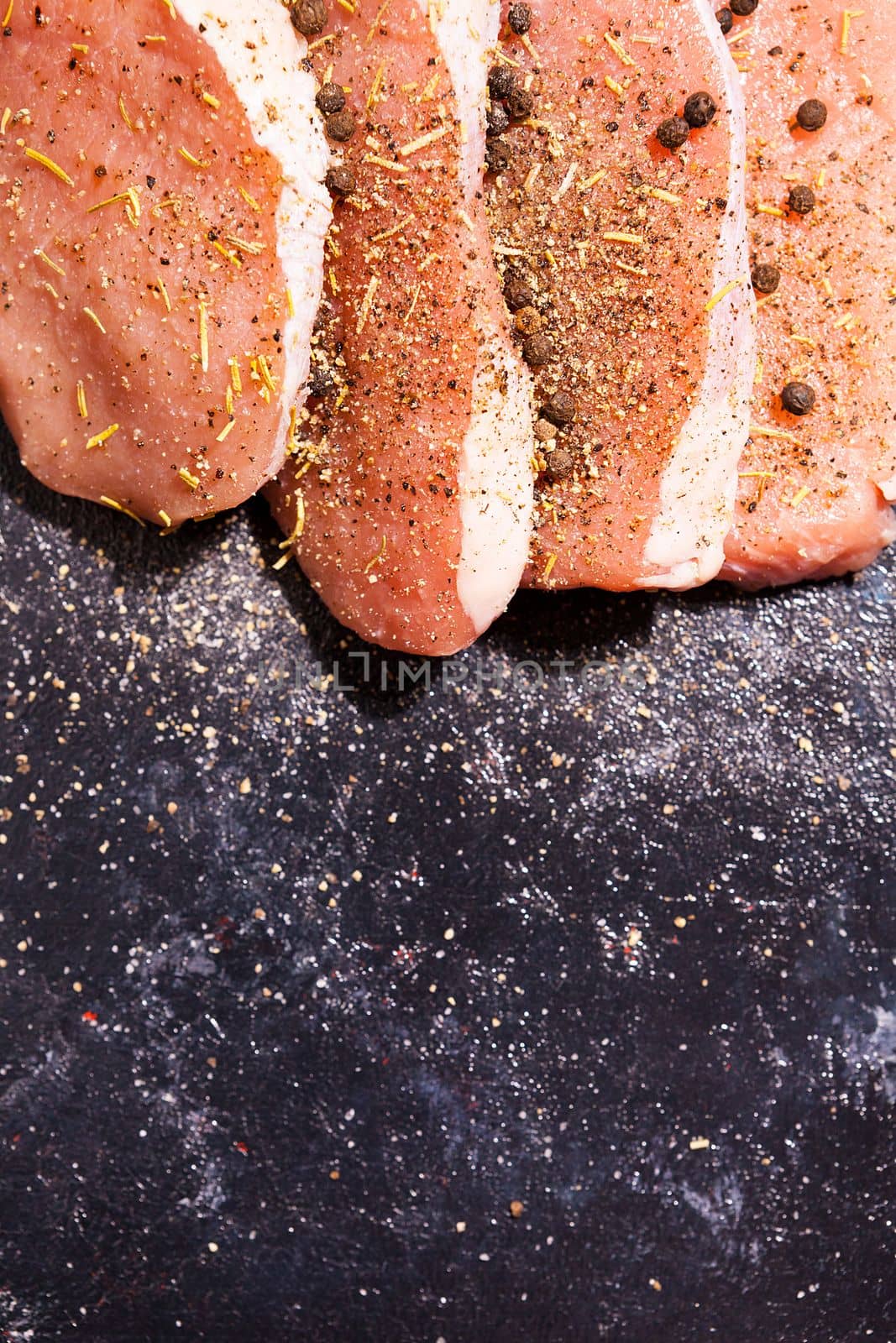 Top close up view on uncooked meat seasoned with spices, pepper by DCStudio