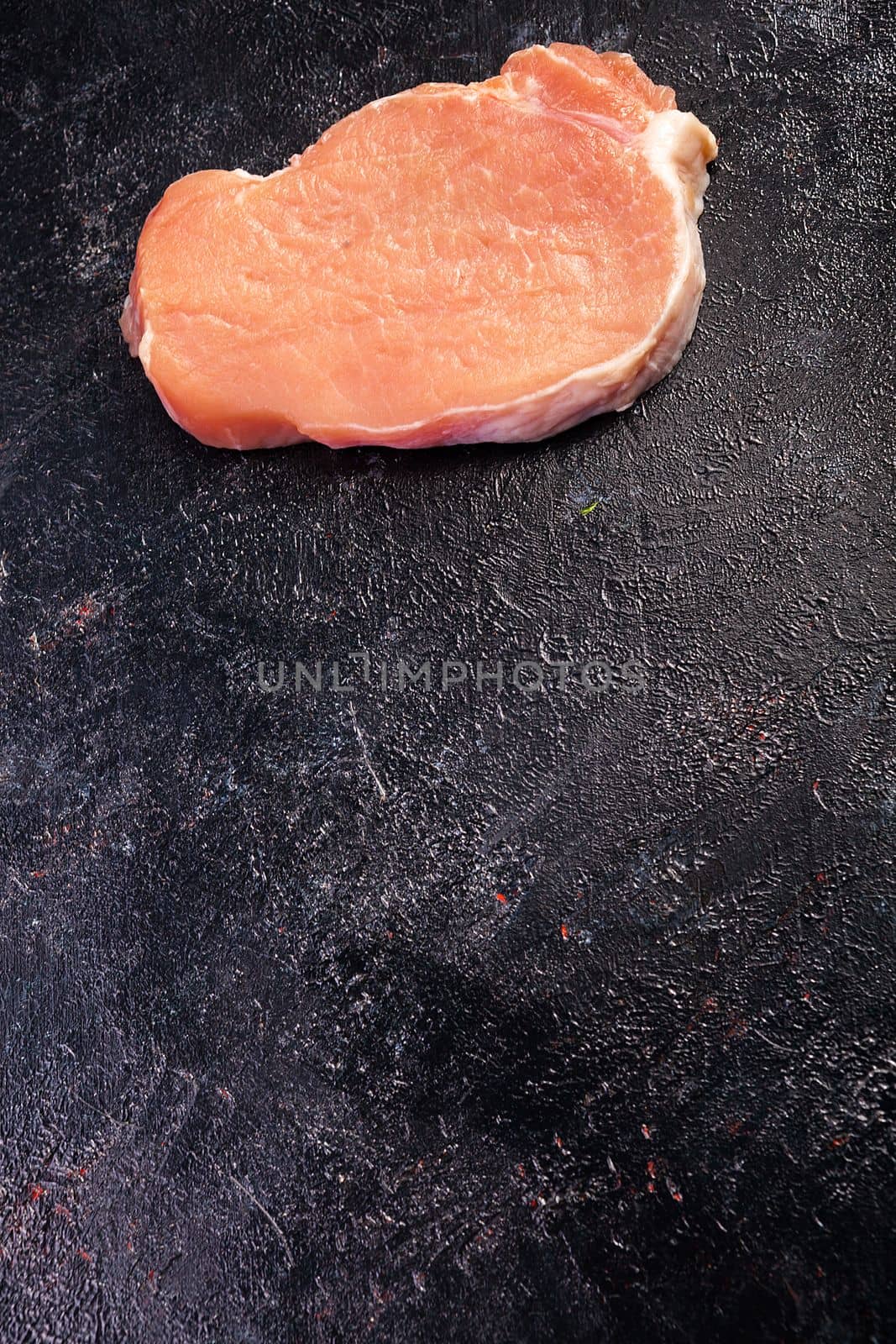 Top view of fresh raw meat on on black wooden table by DCStudio
