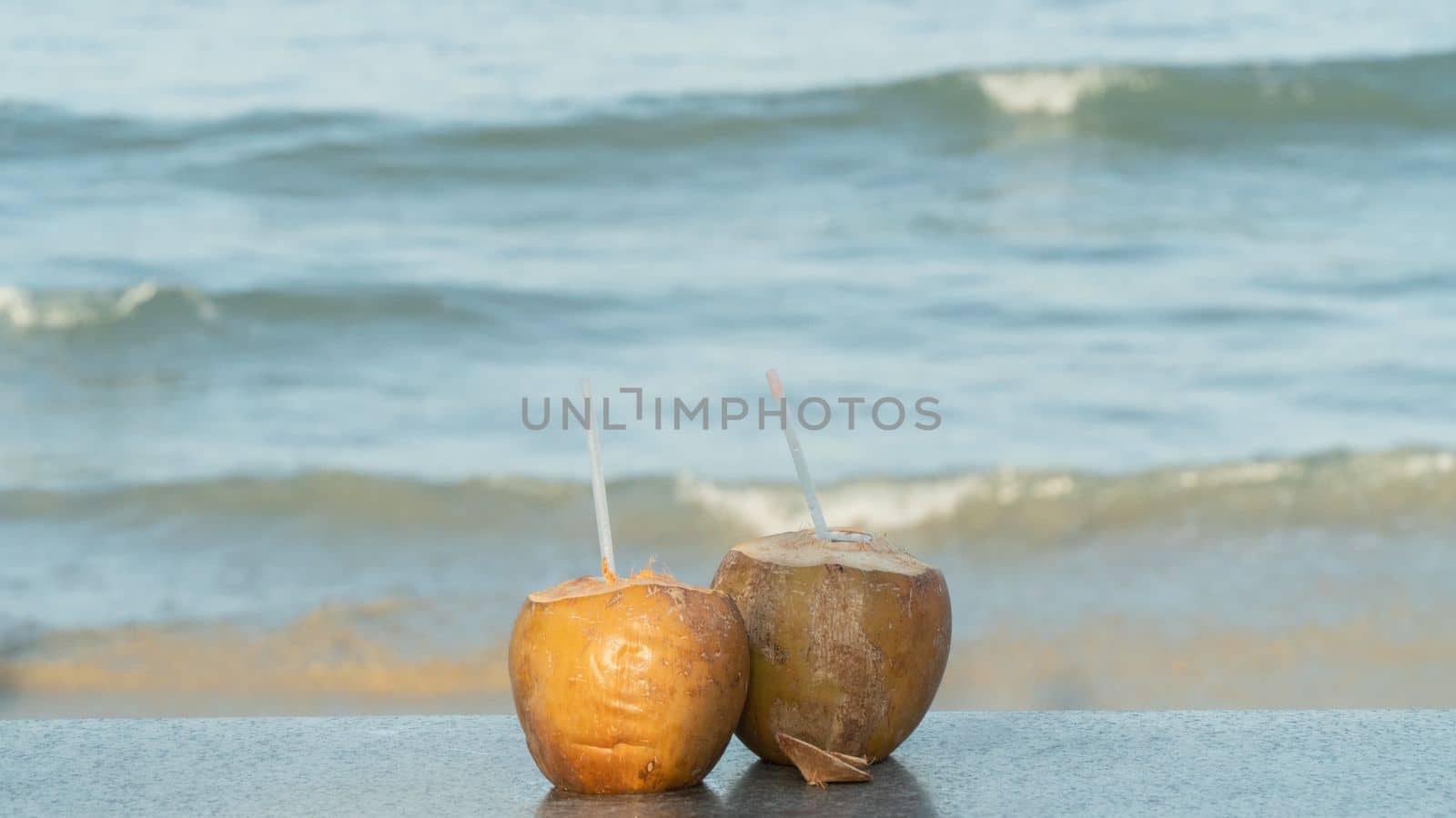 Two coconuts with straws for drinking on the background of the sea. High quality photo