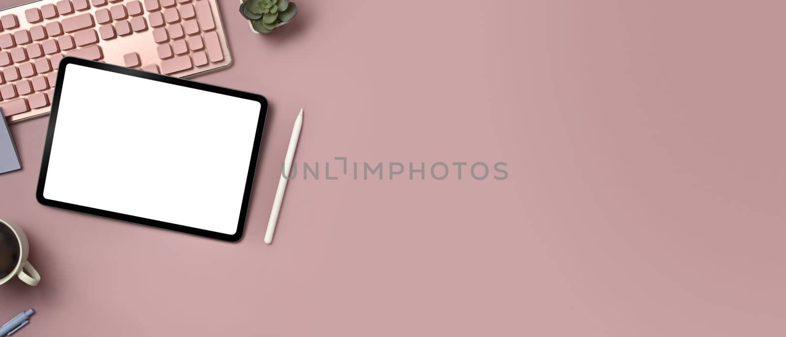 Digital tablet, keyboard, coffee cup and potted plant on pink background. Copy space for text information or content.