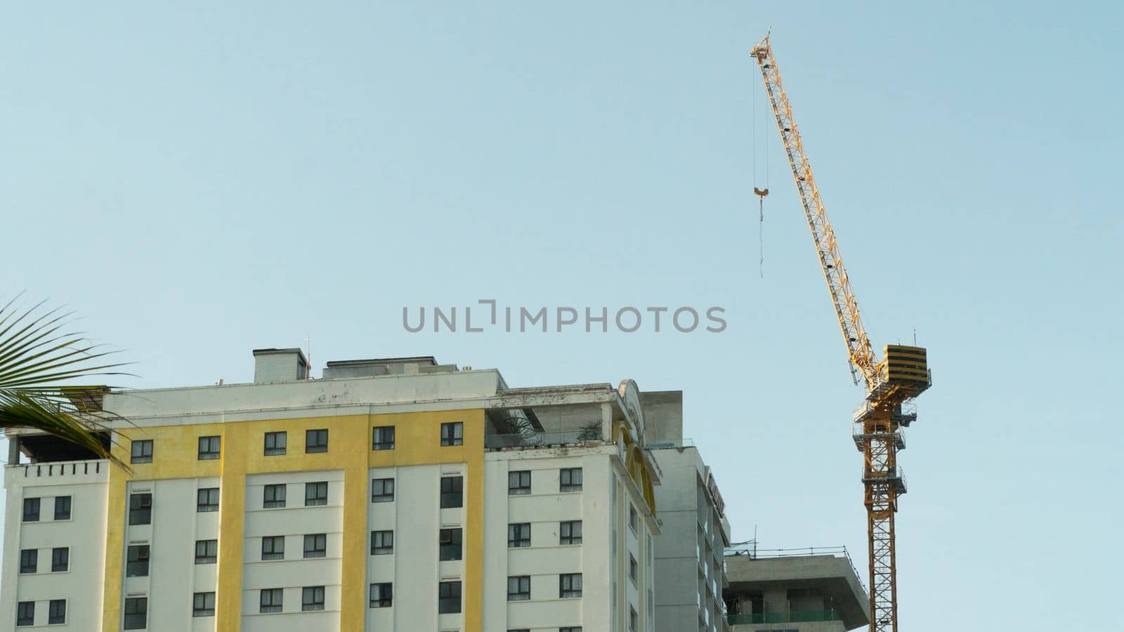 Construction tower crane on the background of a multi-storey building under construction. High quality photo