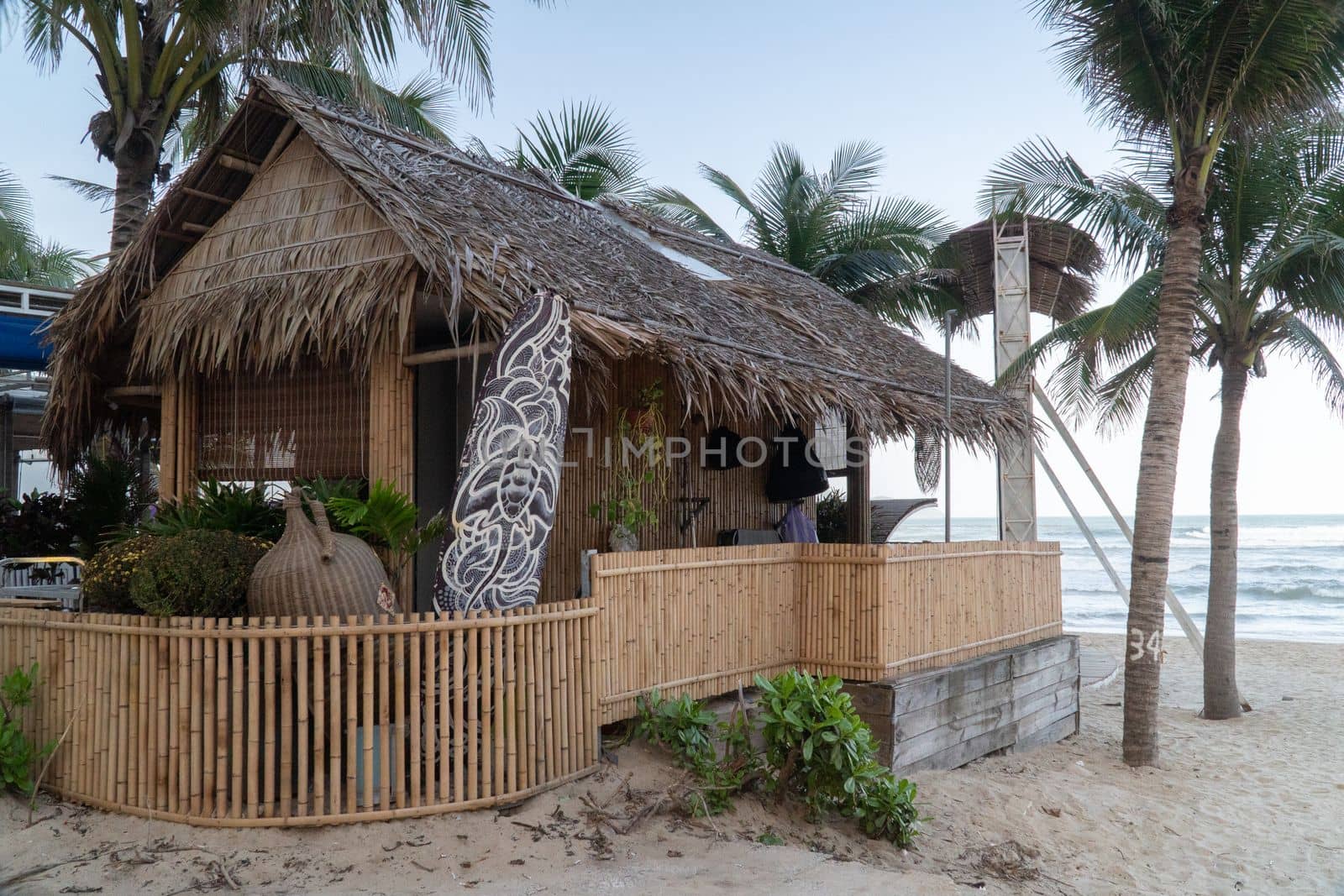 Beach bungalow made of palm leaves on the beach with a surfboard. High quality photo
