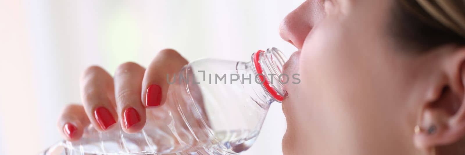 Young woman drinks water from bottle closeup by kuprevich