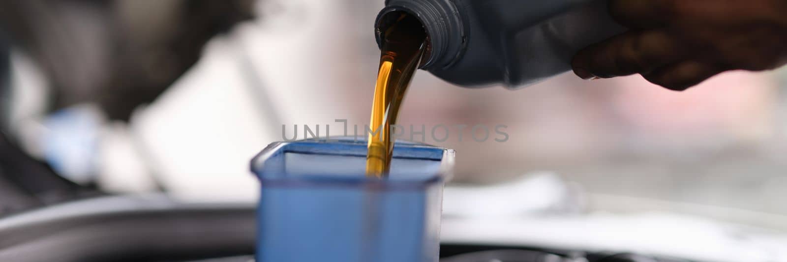 Mechanic pouring engine oil into engine in car service. Services and auto repair shop business concept